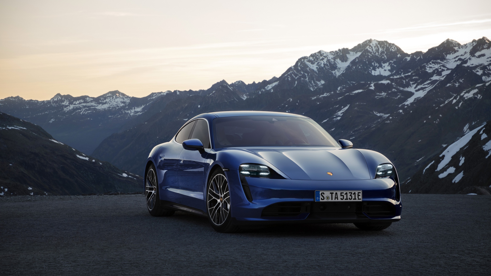 Синий стильный автомобиль Porsche Taycan Turbo 2019 года на фоне гор