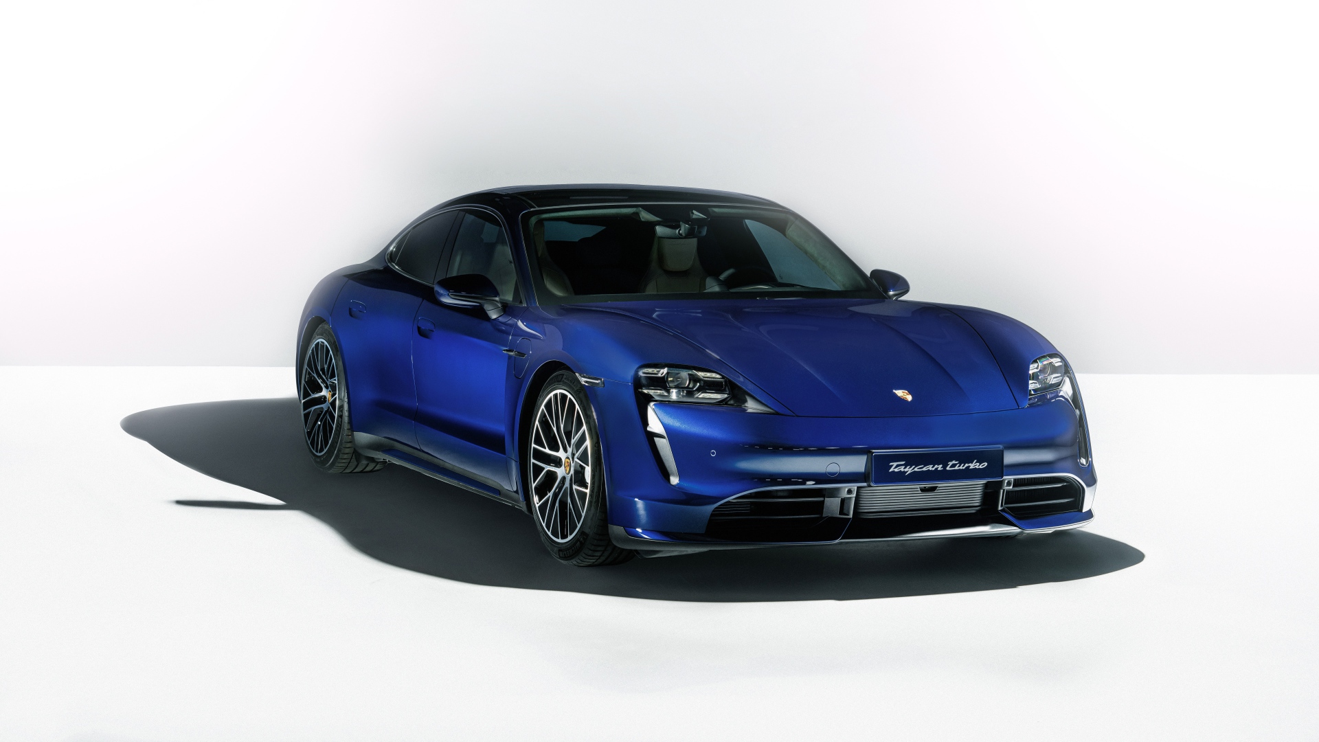 Синий автомобиль Porsche Taycan Turbo 2019 года на сером фоне