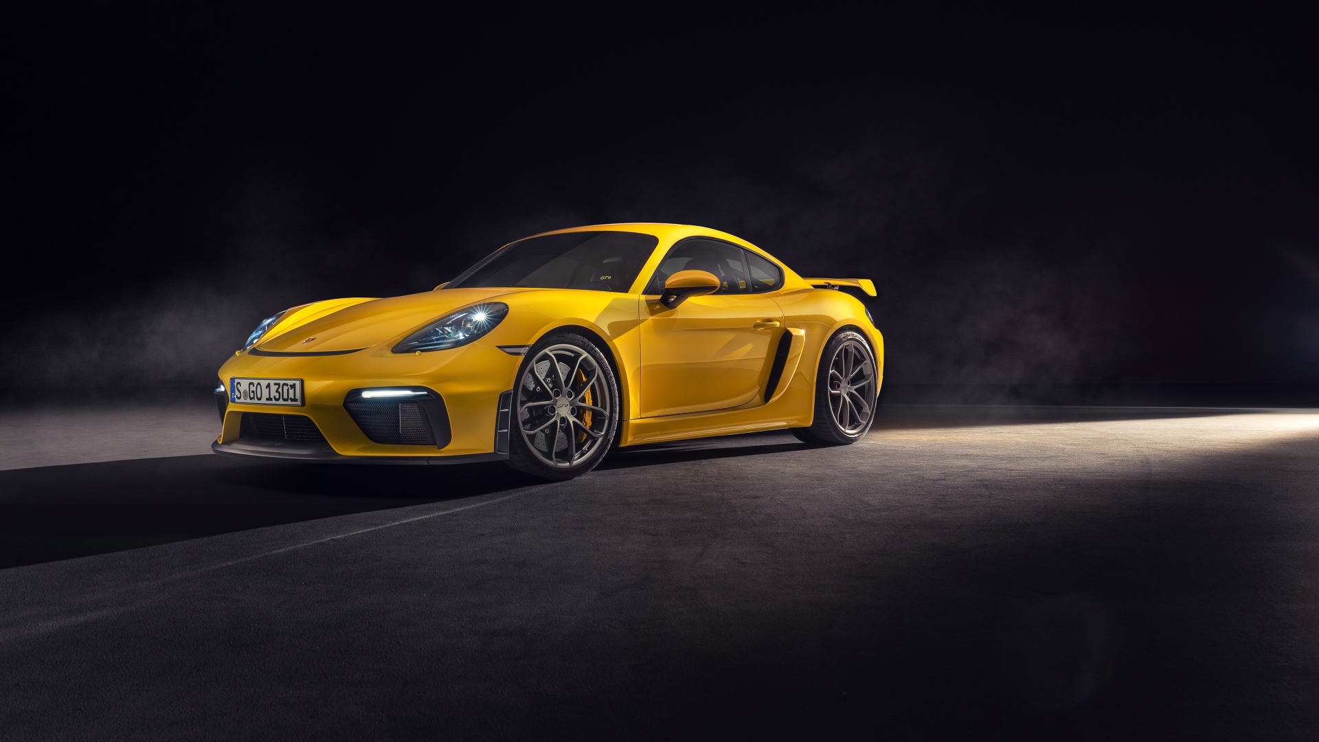 Желтый спортивный автомобиль Porsche 718 Cayman GT4, 2019 года на сером фоне