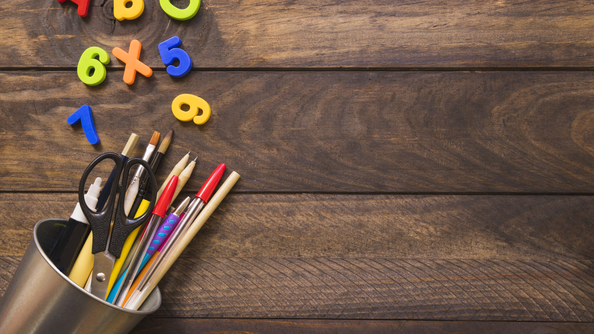 Банка с канцелярскими принадлежностями на деревянном столе с цифрами