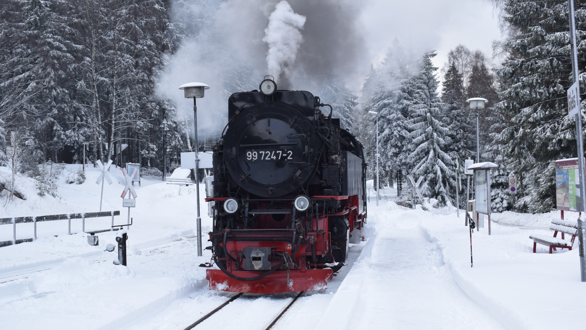 Старый локомотив на заснеженной станции у леса зимой