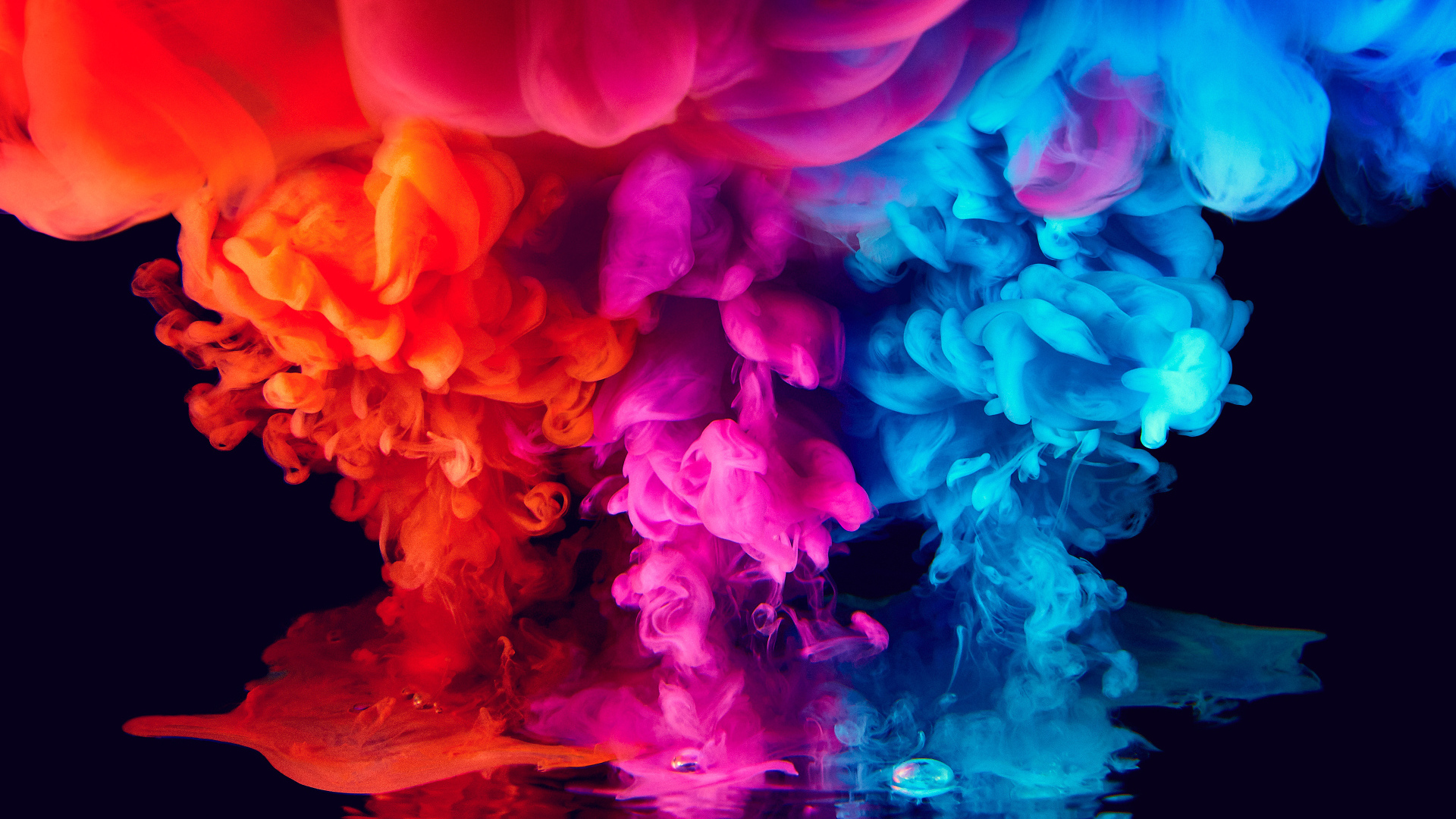 Красный, голубой и сиреневый дым на черном фоне