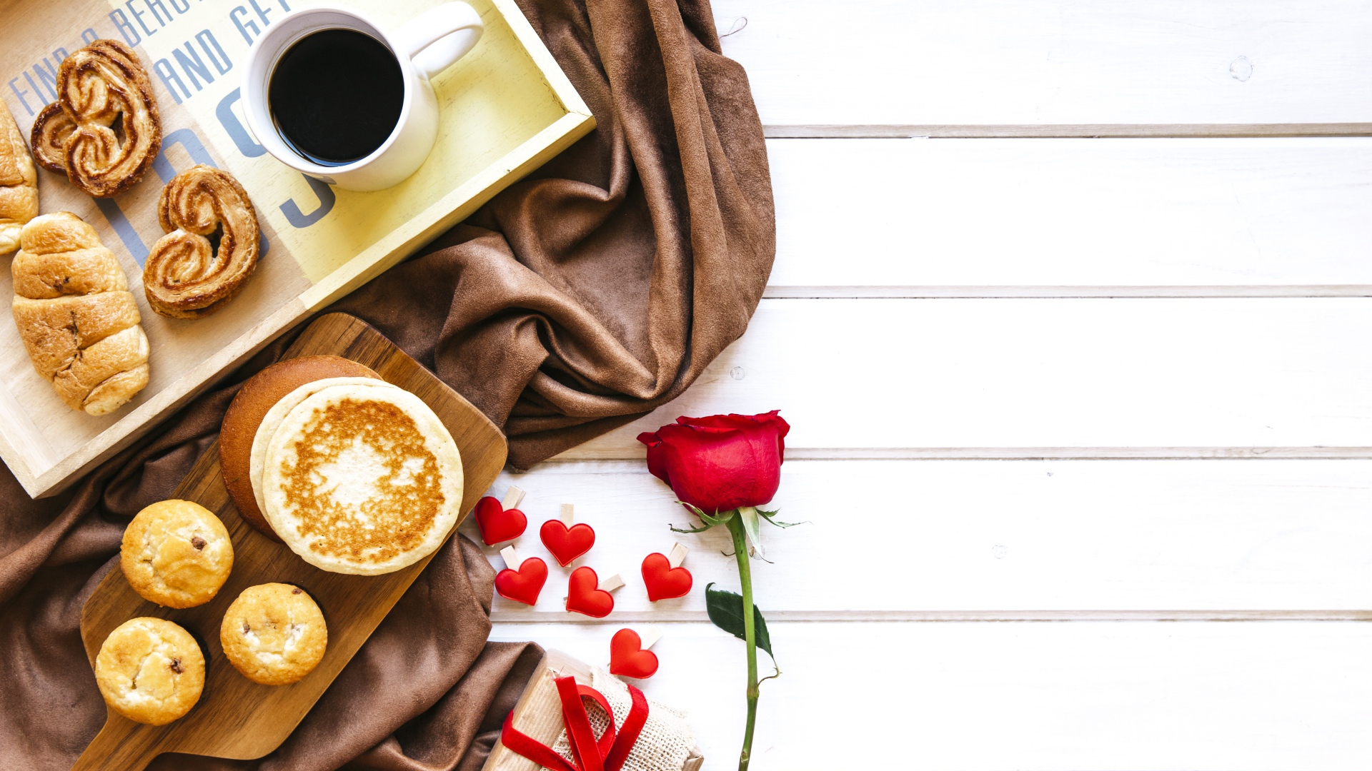 Выпечка на столе с кофе, подарком и красной розой