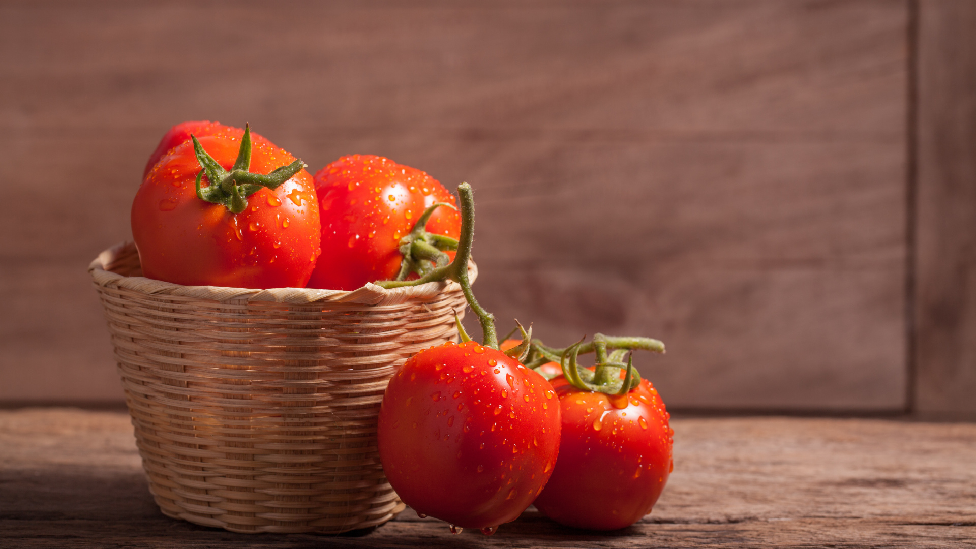 Красивые красные мокрые помидоры в корзине на столе 