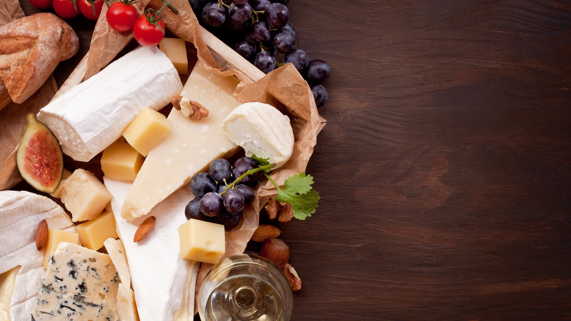 Сыр на столе с виноградом, инжиром и помидорами