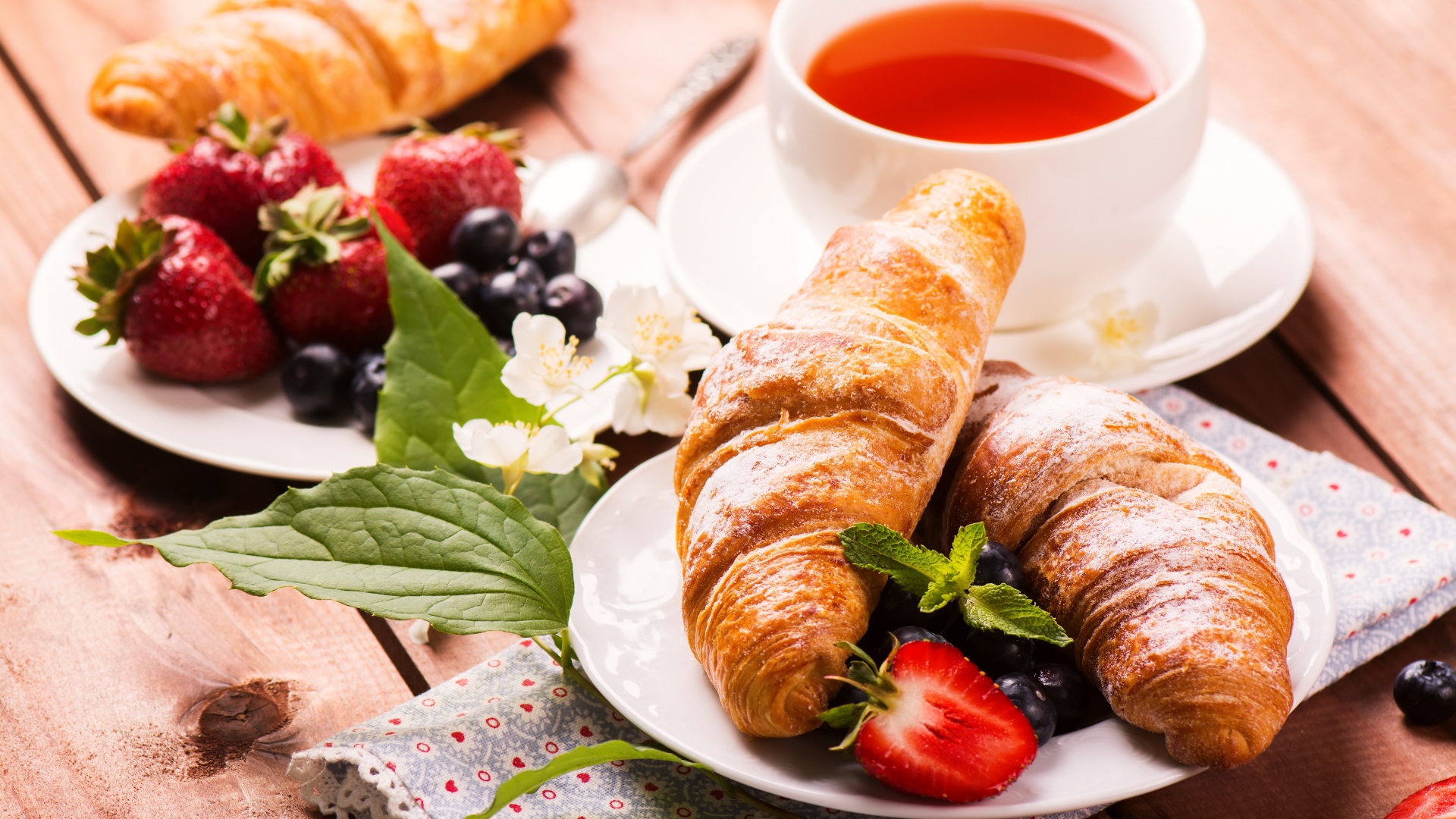 Круассаны на столе с ягодами и чашкой чая