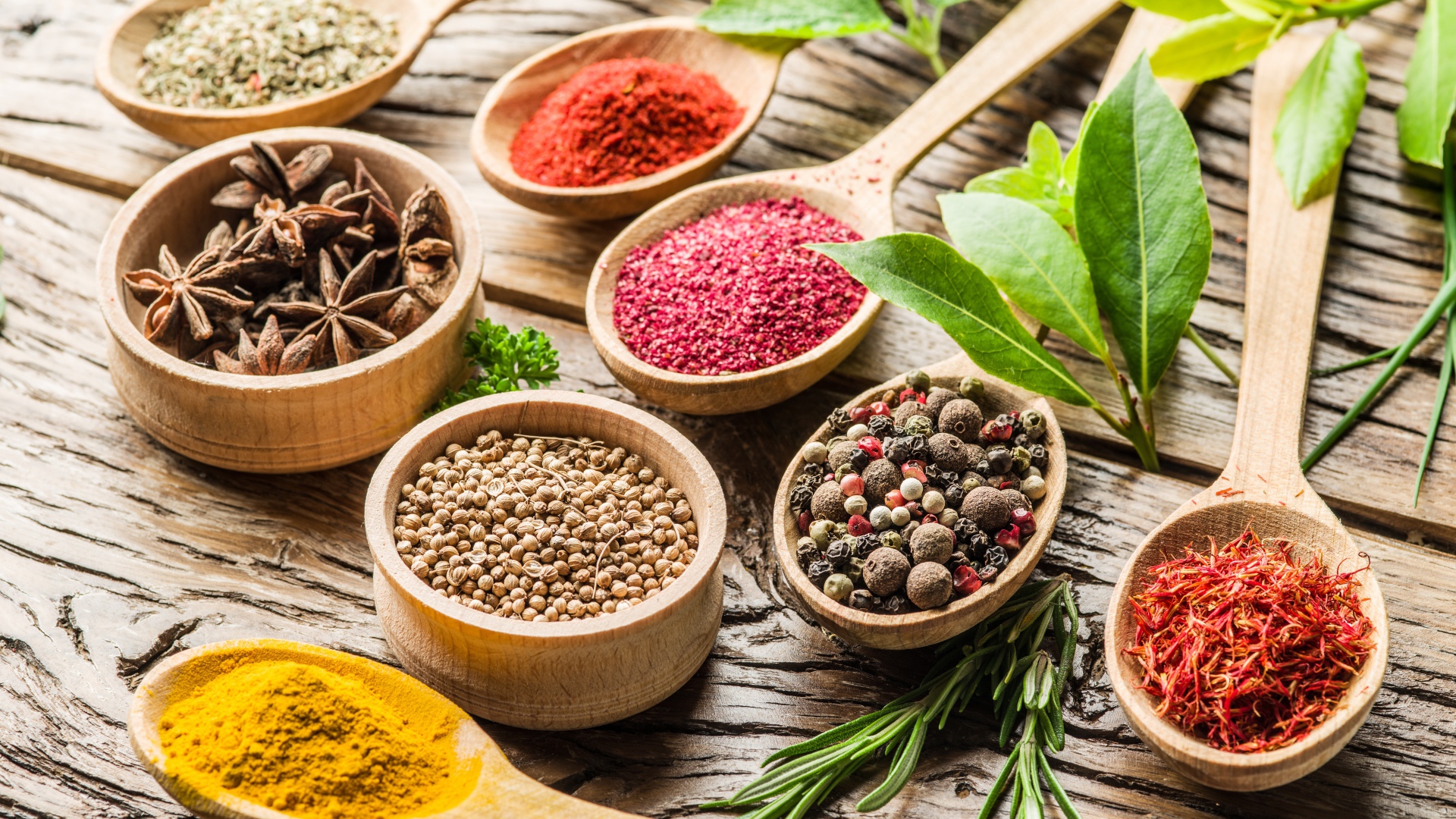 Разные специи в деревянных ложках на столе 