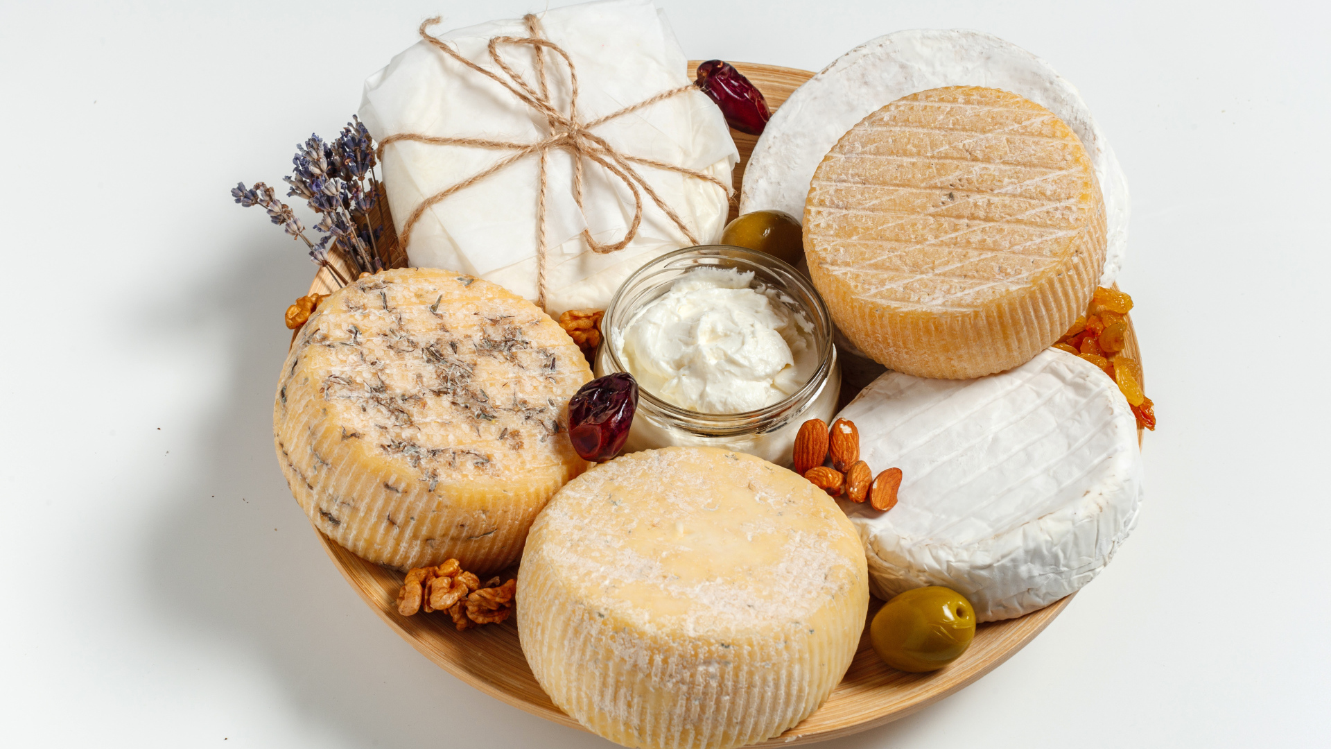 Разные виды сыра на тарелке с орехами на сером фоне