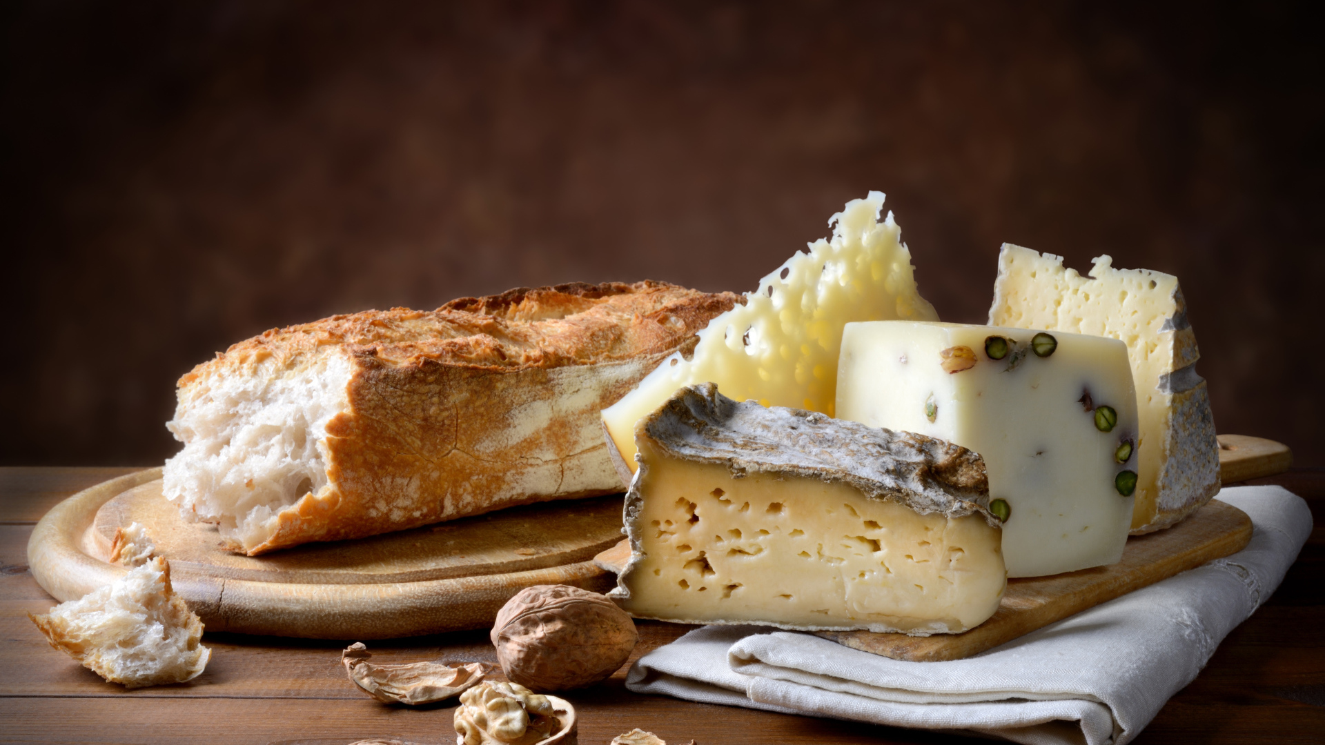 Разные виды сыра на столе батоном и грецкими орехами