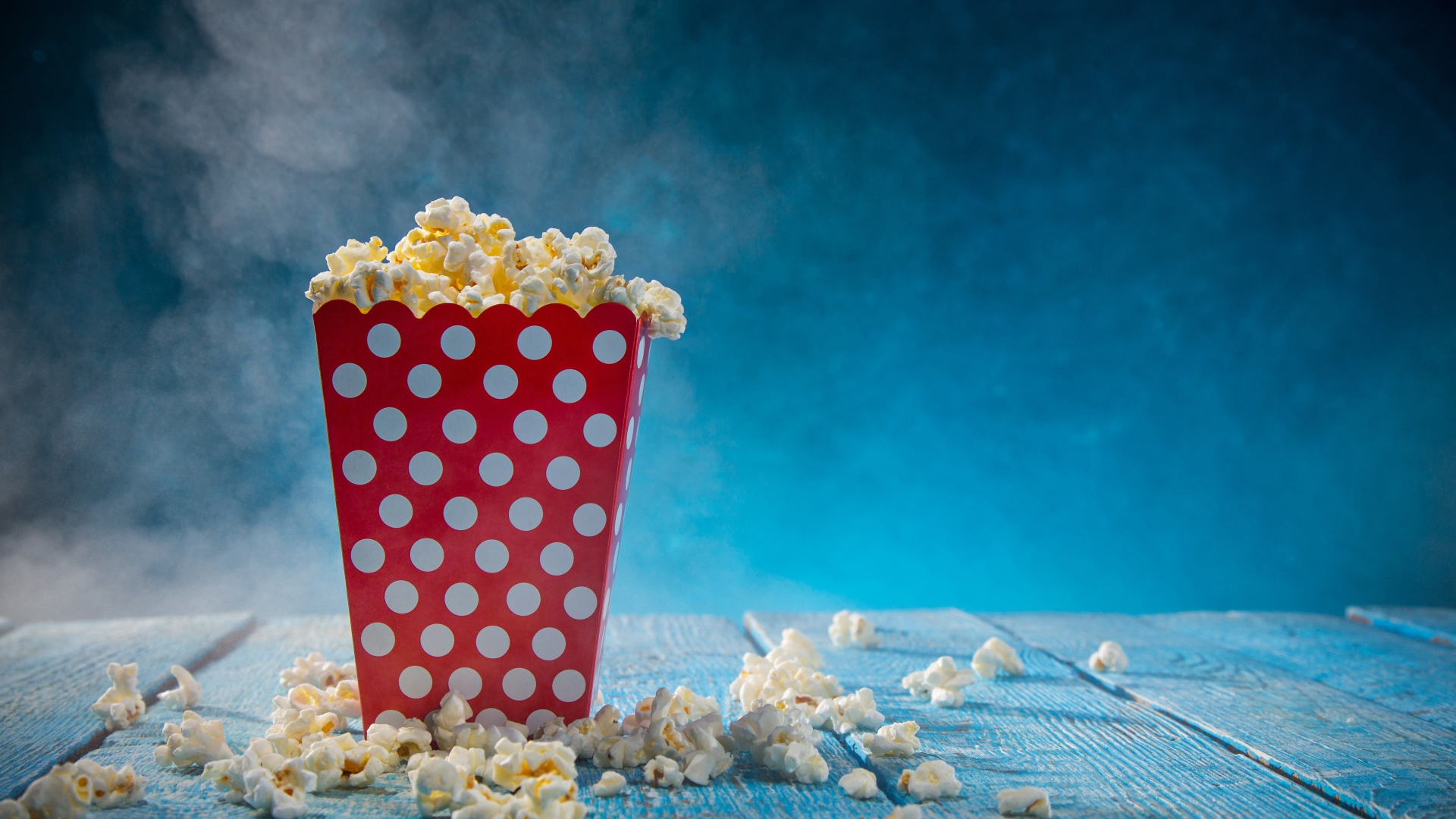 Попкорн в картонном пакете на голубом столе 