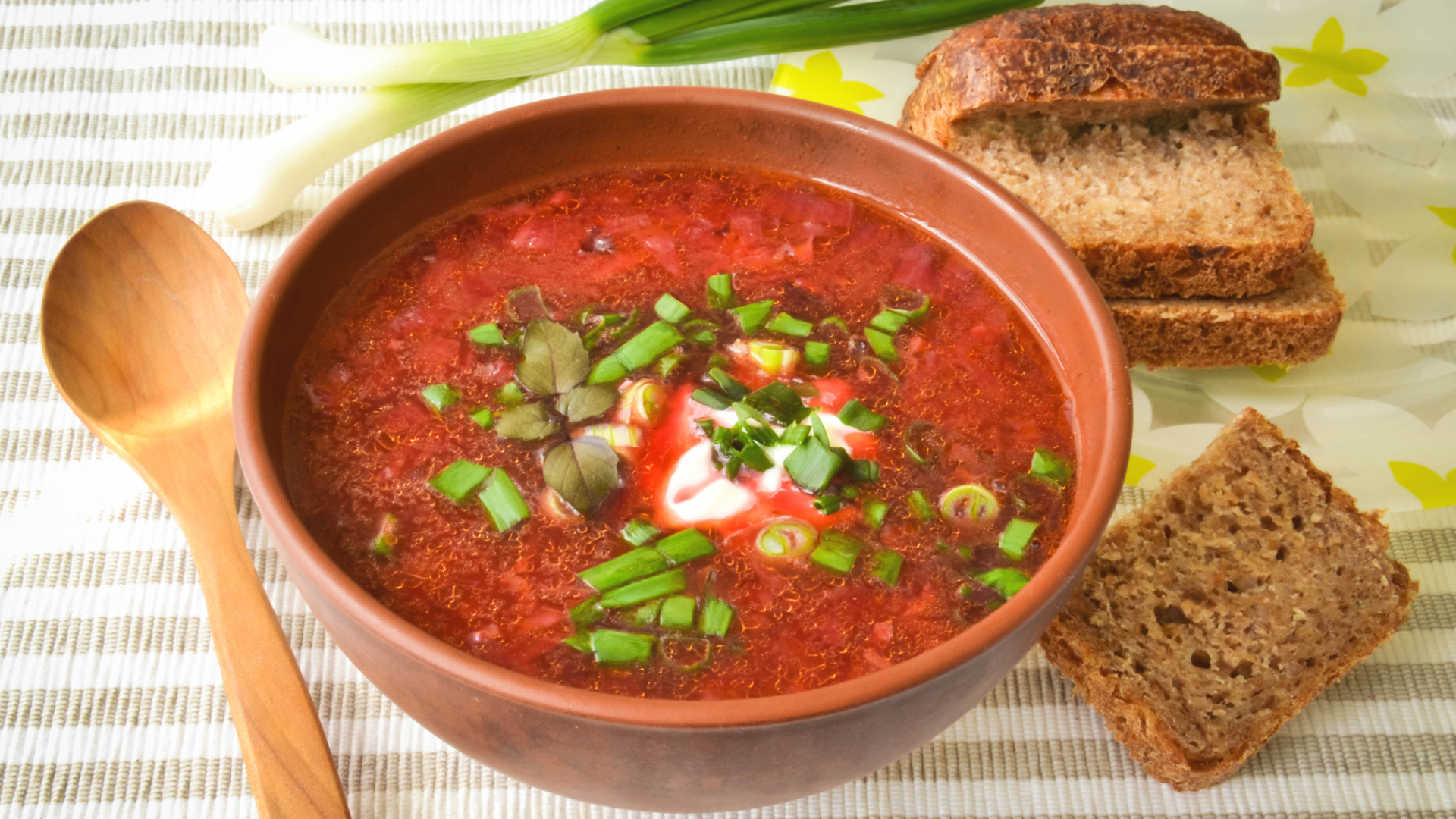 Красный борщ с луком на столе с хлебом 