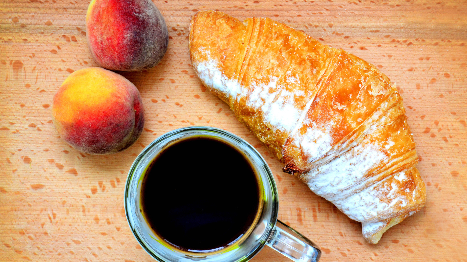 Два персика на столе с кофе и круассаном