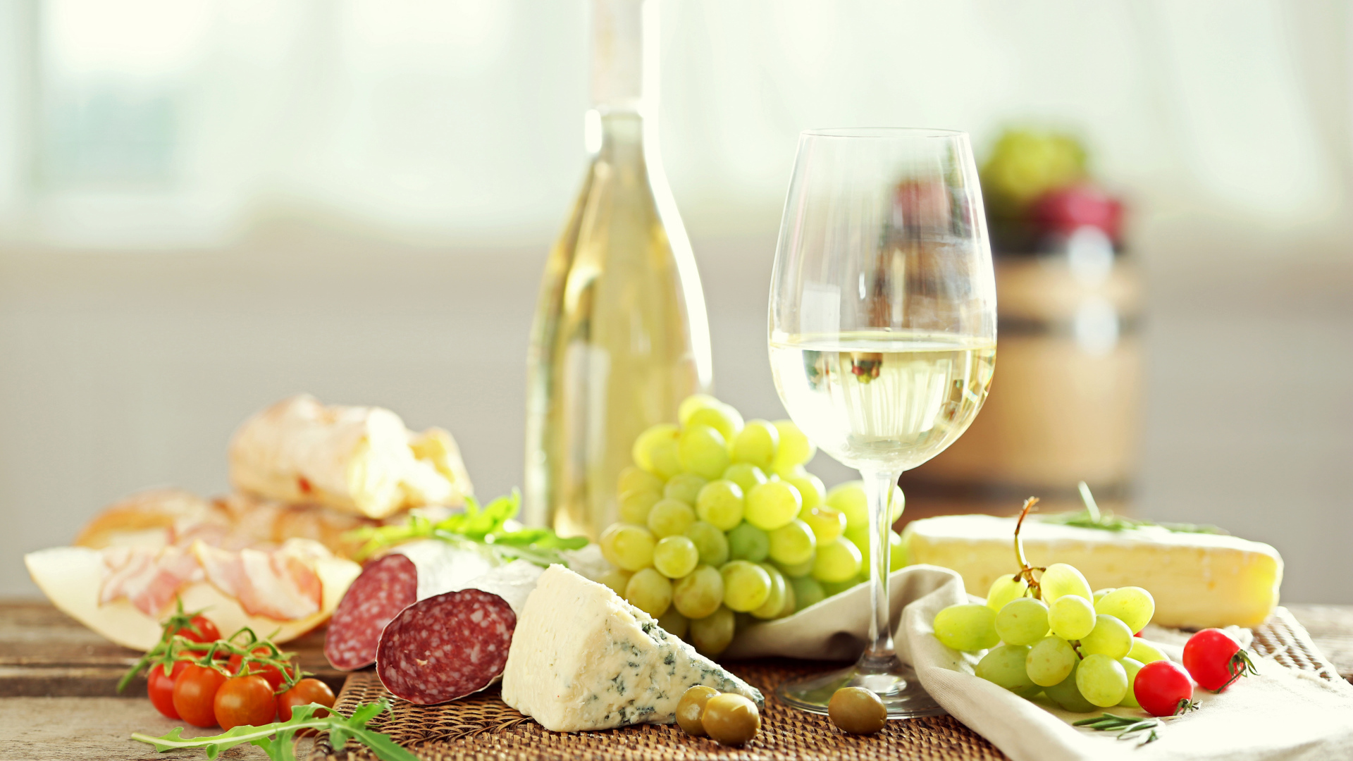 Белое вино на столе с сыром, колбасой и виноградом