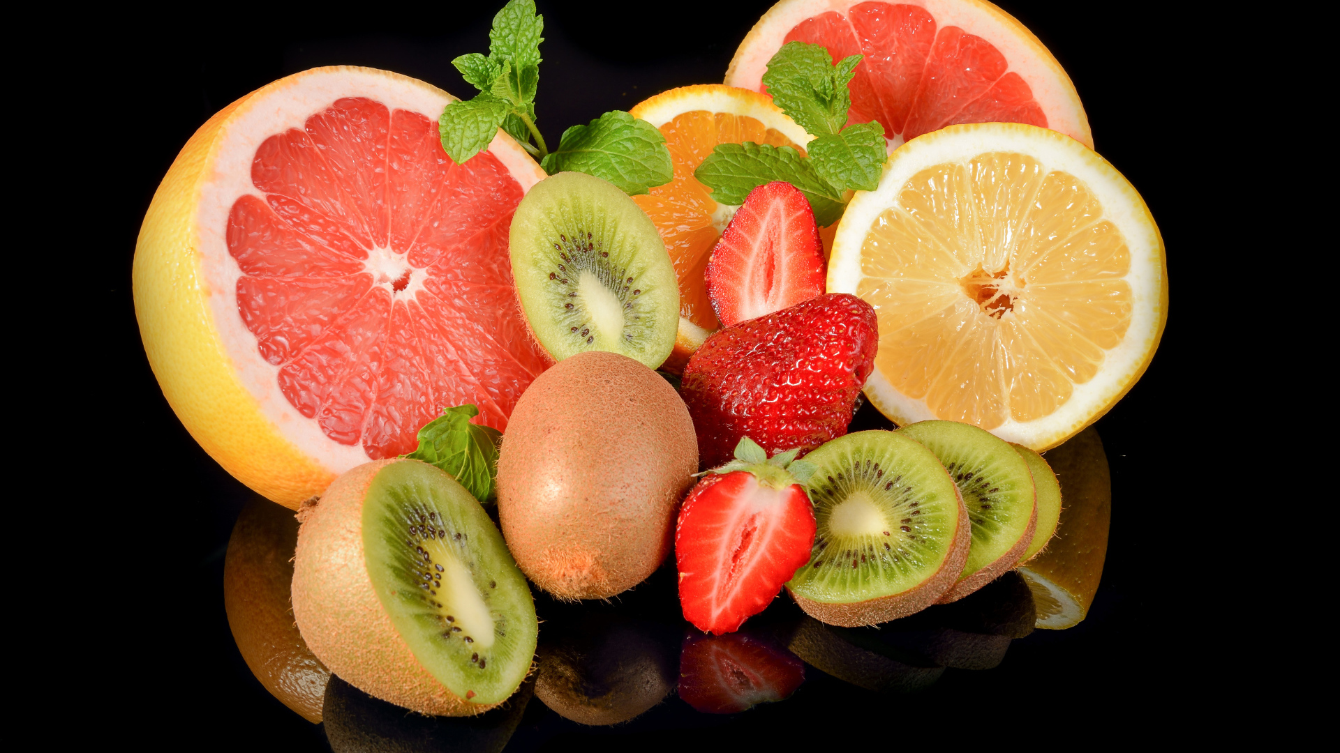 Цитрусовые фрукты на черном фоне с ягодами клубники 