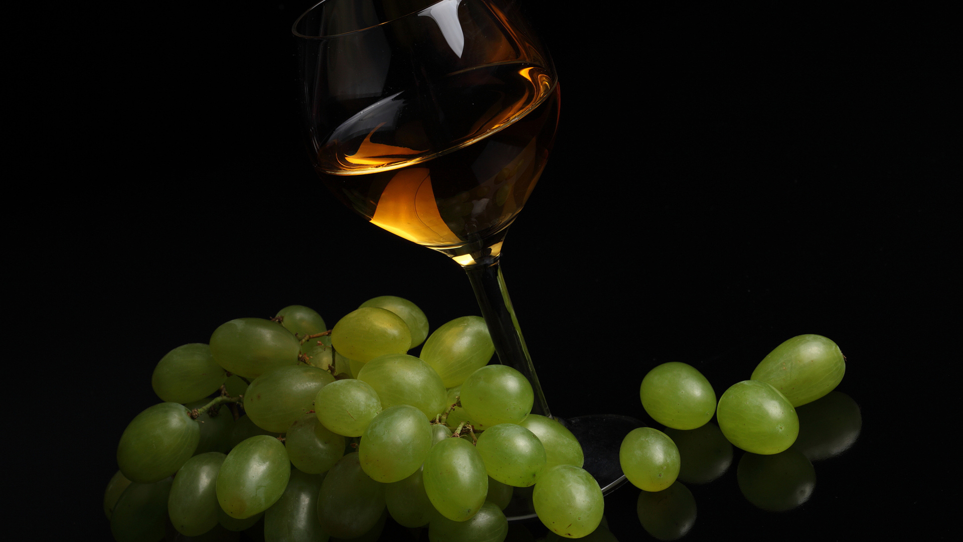 Бокал вина с белым виноградом на черном фоне