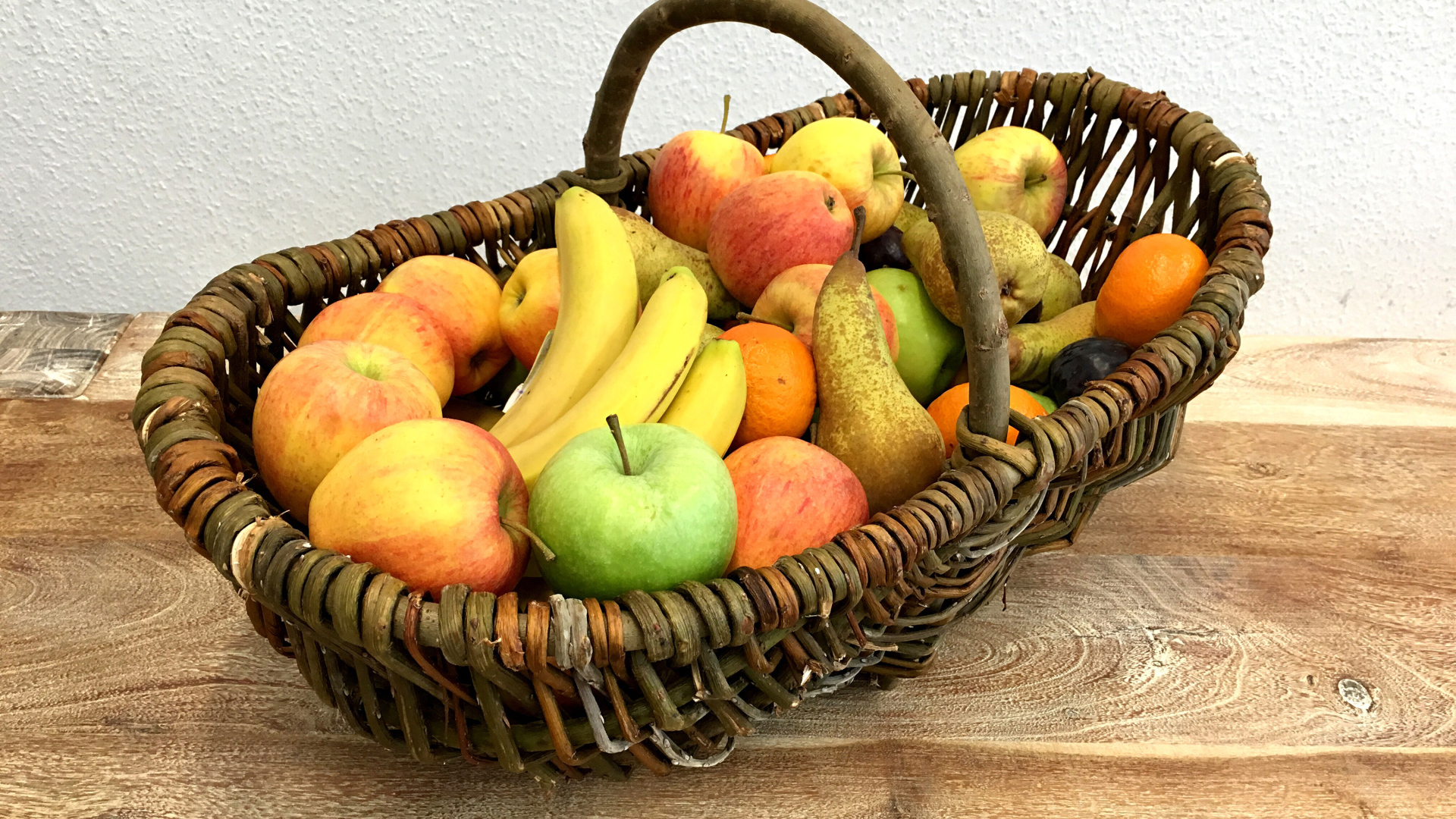 Спелые фрукты в плетеной корзине на столе
