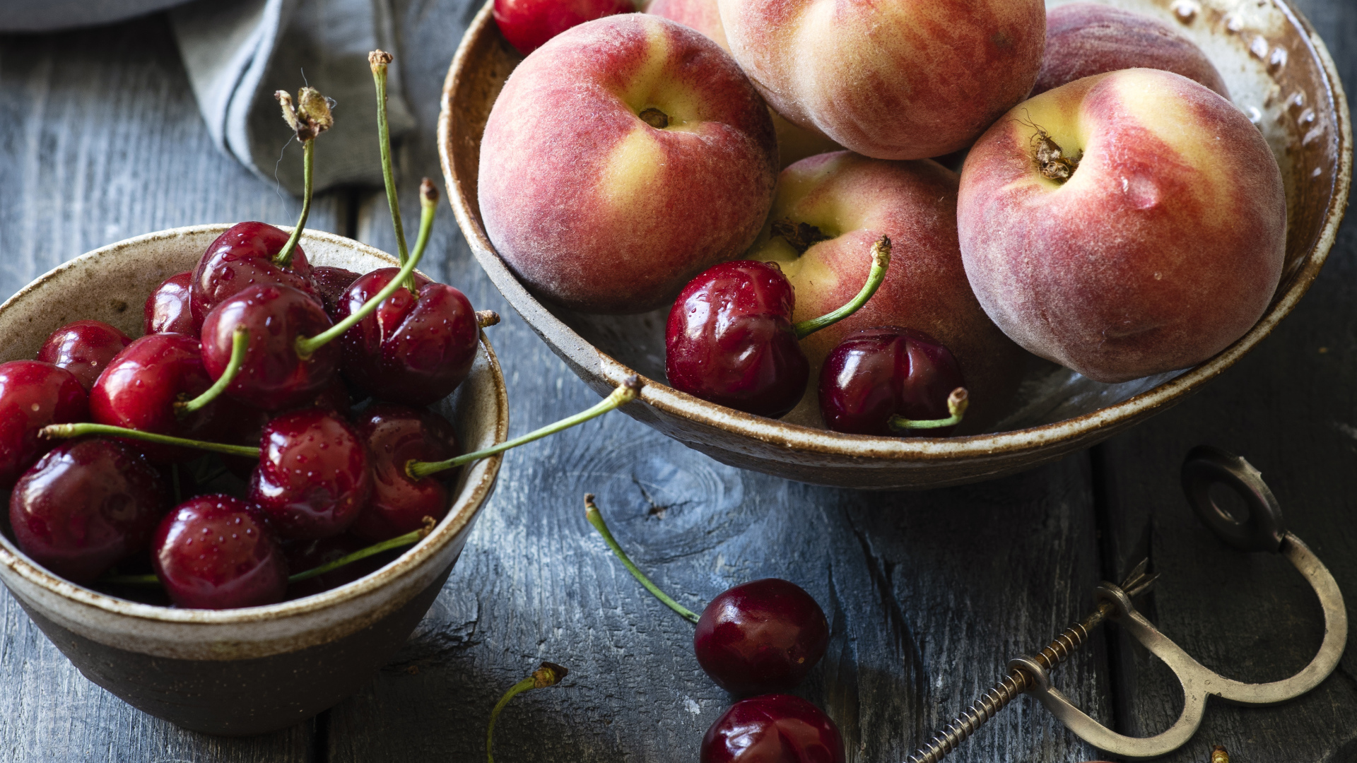 Спелые персики в миске на столе с черешней