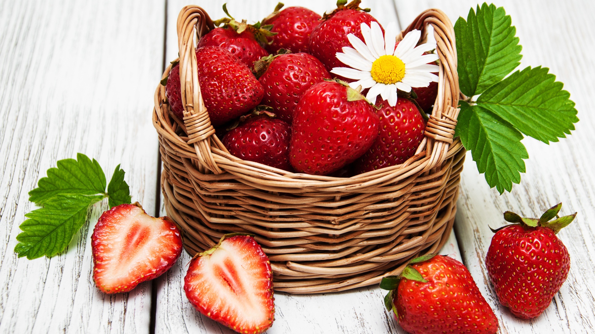 Плетеная корзинка с клубникой, ромашкой и зелеными листьями