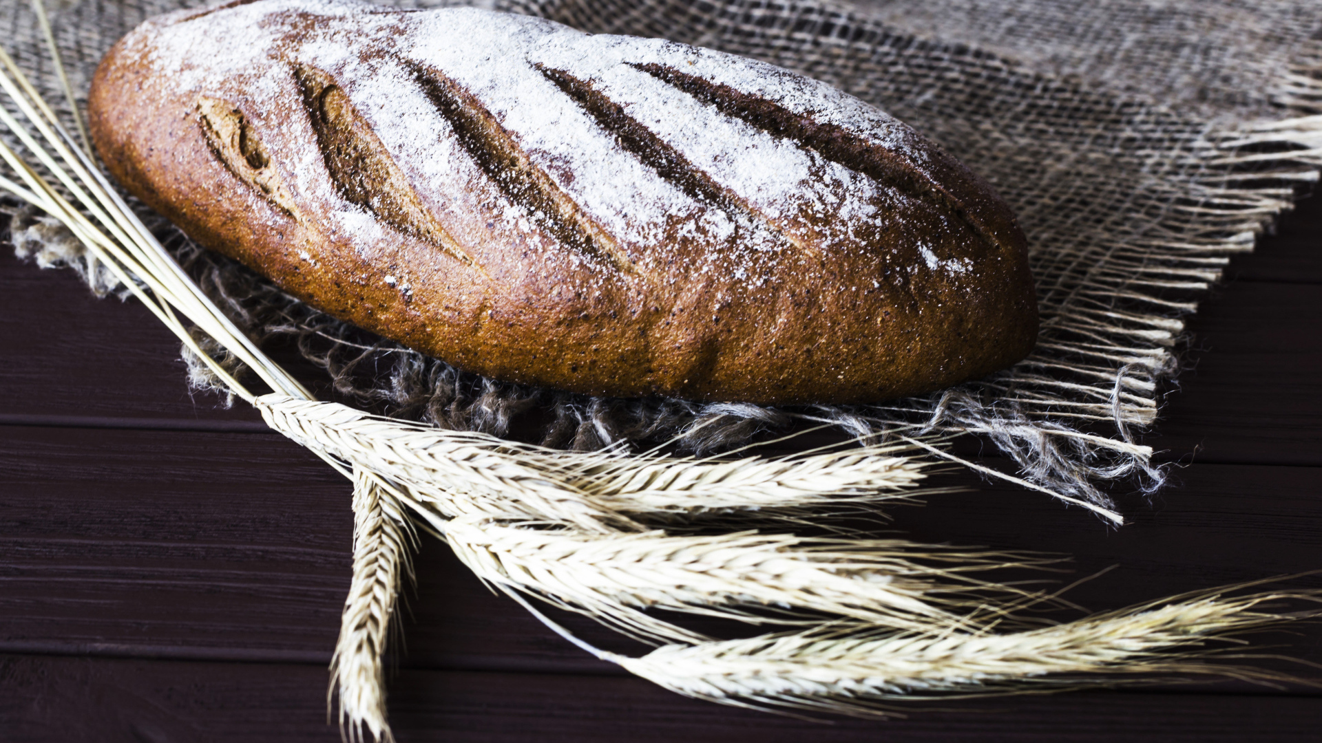 Буханка свежего хлеба на столе с колосьями пшеницы