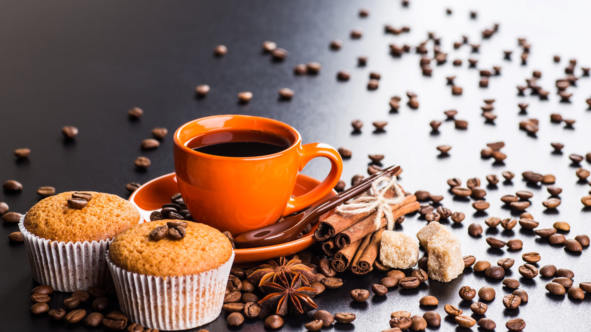 Чашка кофе на столе с кексами, кофейными зернами, корицей и бадьяном