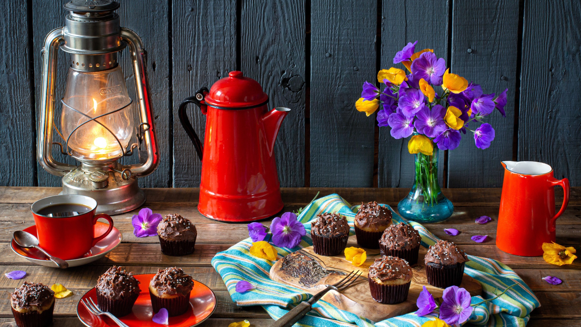 Аппетитные свежие кексы с кремом на столе с кофе, лампой и букетом цветов