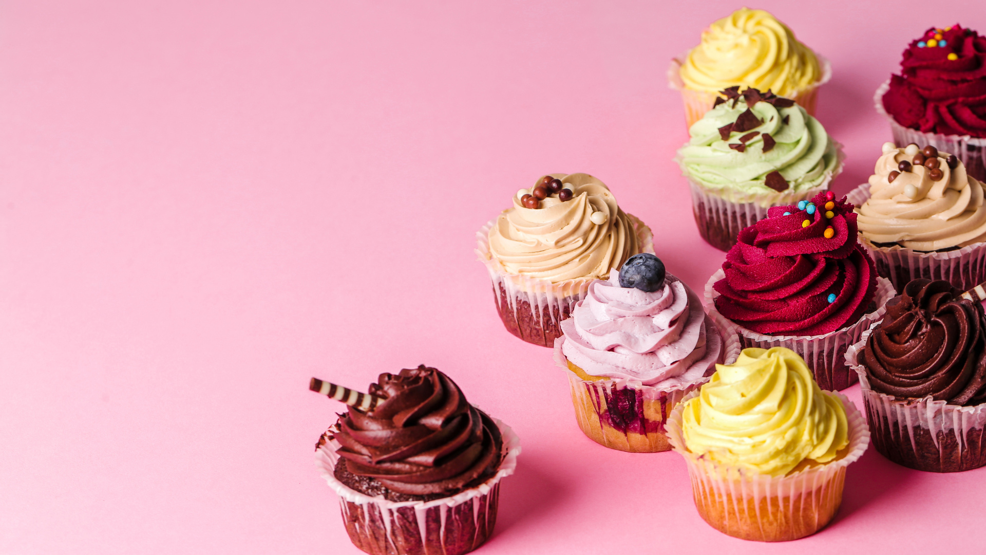 Кексы с разноцветным кремом на розовом фоне