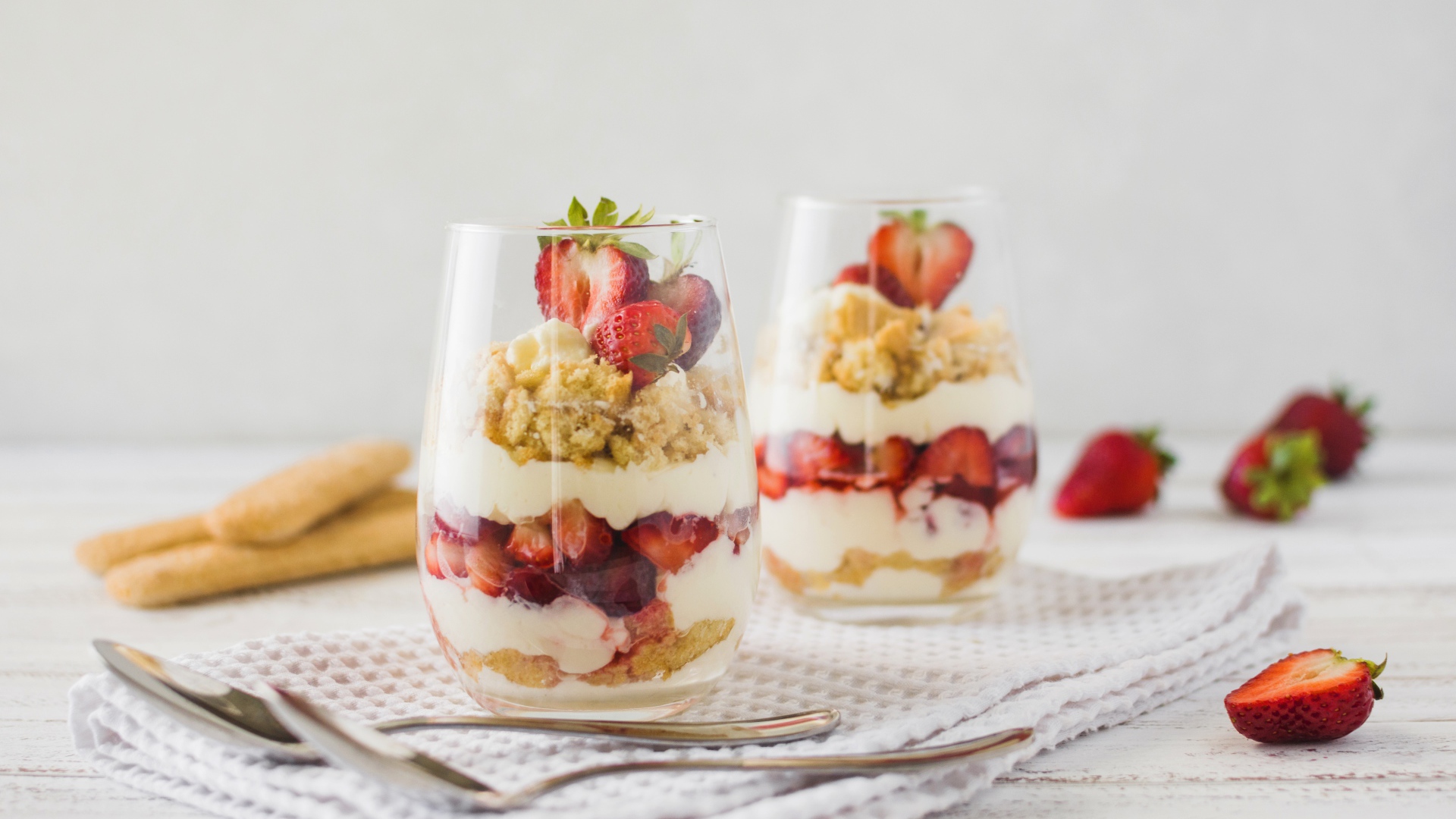 Десерт с клубникой в стеклянных стаканах на столе 