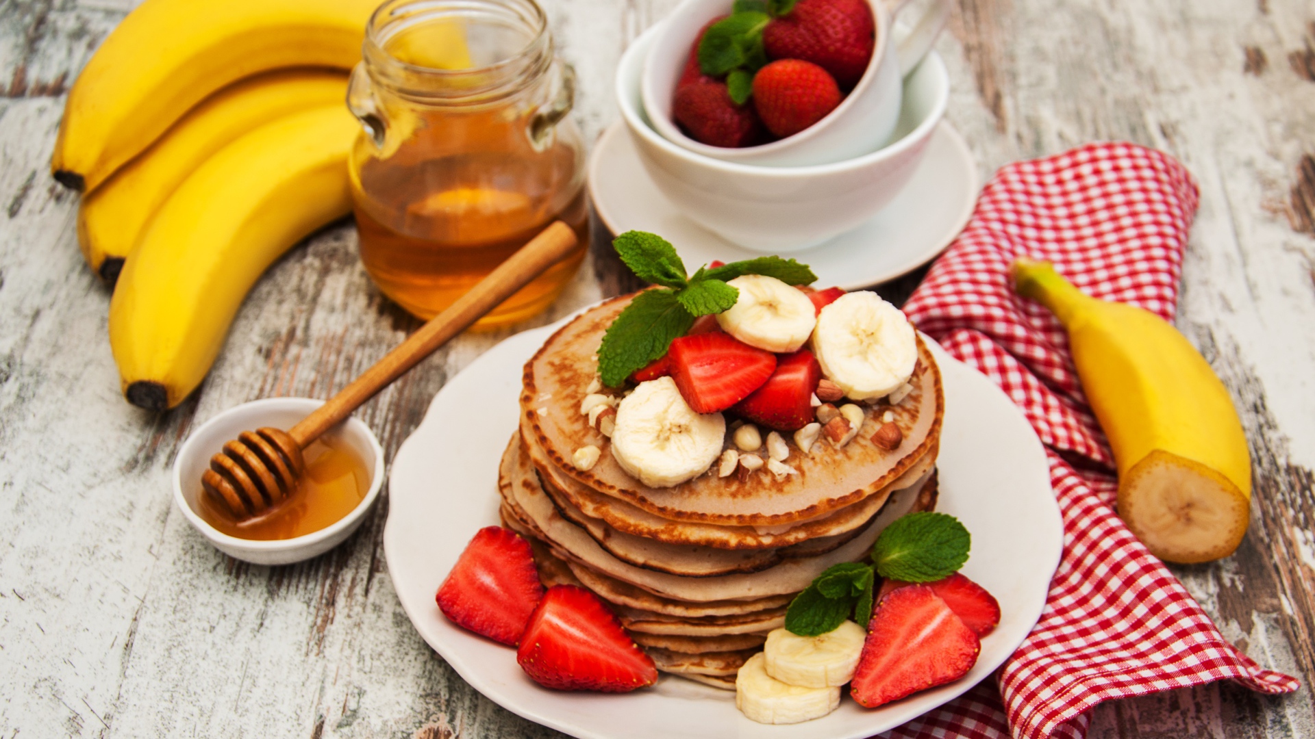 Fritters with bananas and strawberries on a table with honey