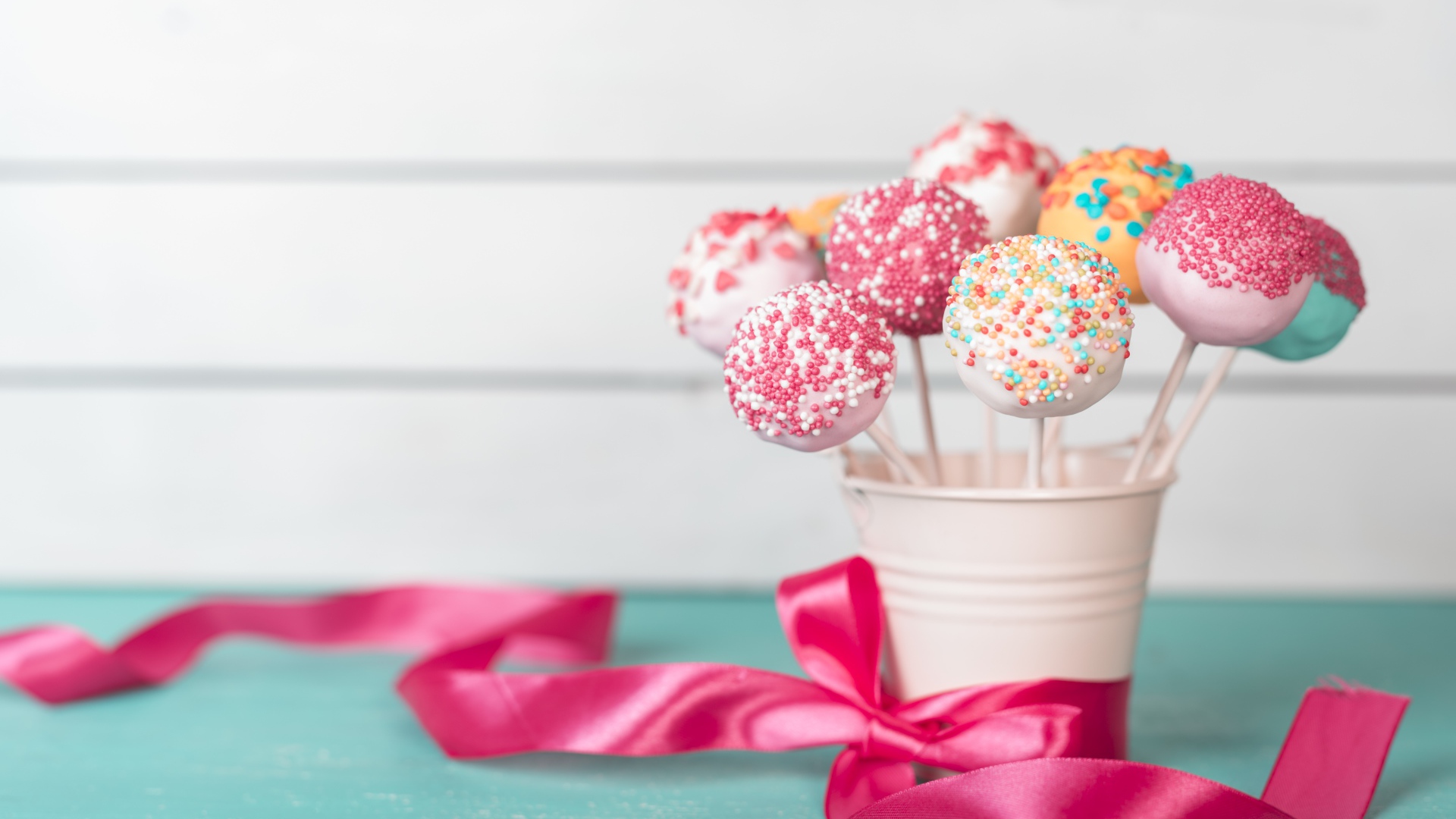 Леденцы в стакане на столе с розовым бантом из ленты