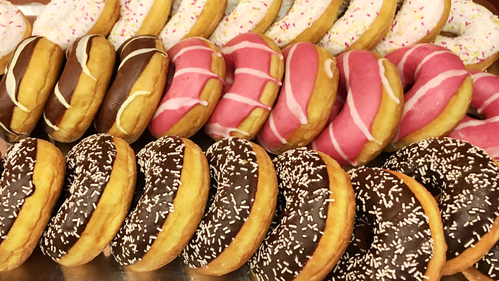 Много вкусных сладких пончиков с глазурью на столе 