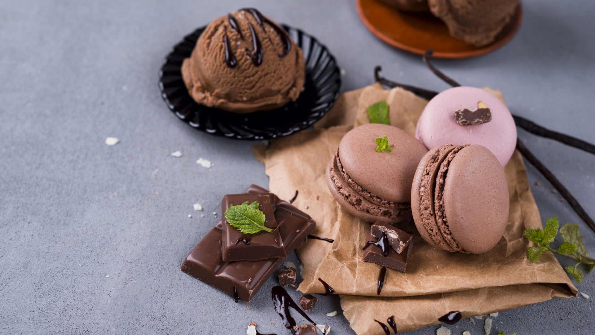 Печенье макарун на серой поверхности с мороженым и шоколадом