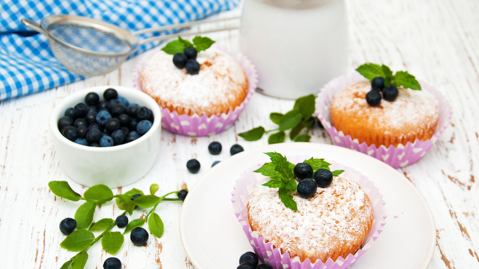 Кексы с сахарной пудрой на столе с молоком и черникой