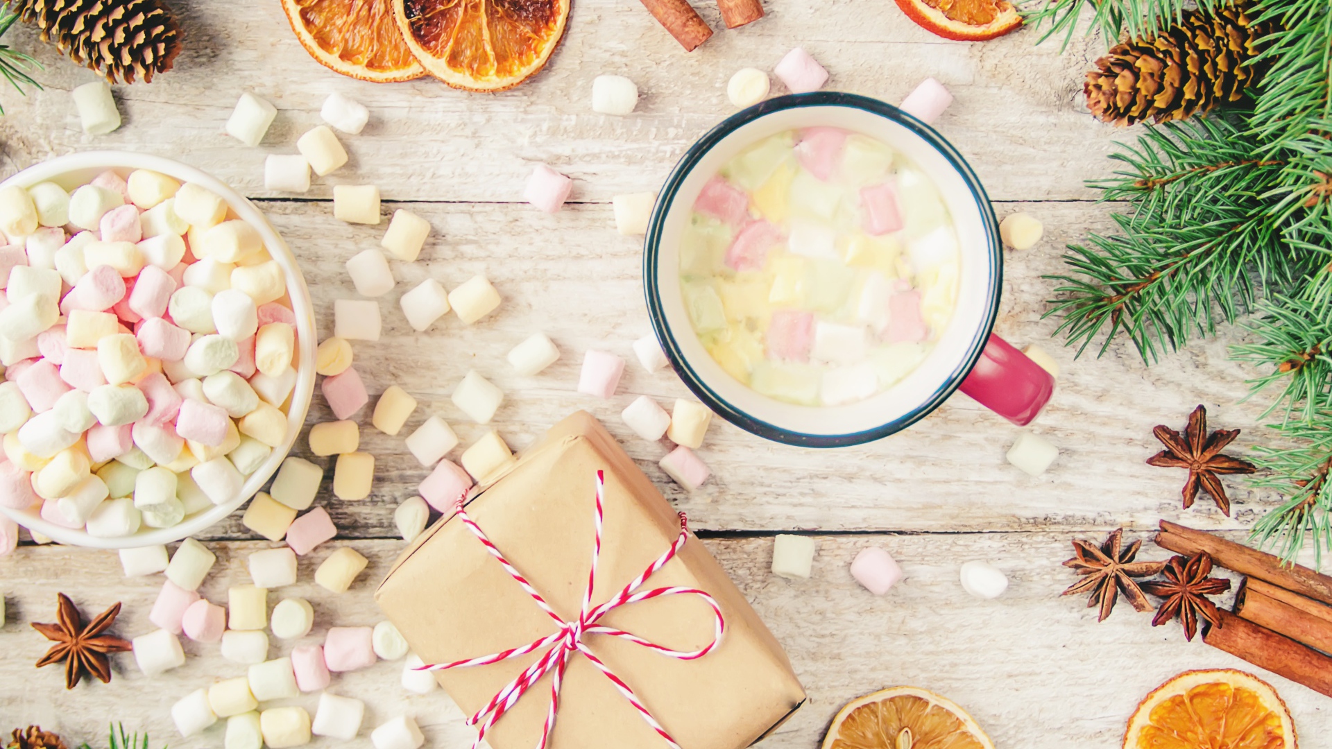 Кружка горячего напитка на столе с маршмеллоу, пряностями и подарком