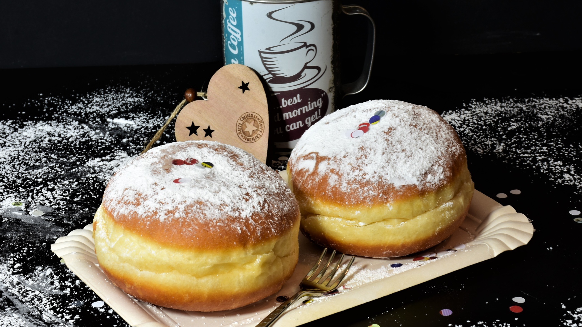Два пышных пончика с сахарной пудрой на черном столе с кофе