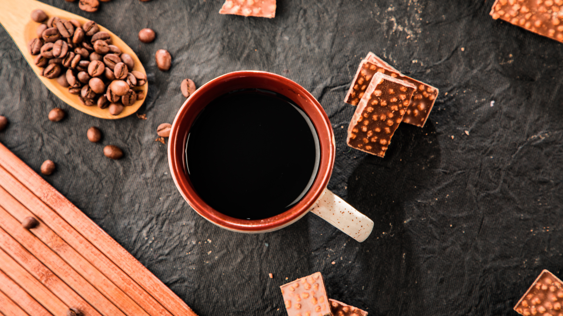 Чашка кофе на столе с кусочками шоколада и кофейными зернами