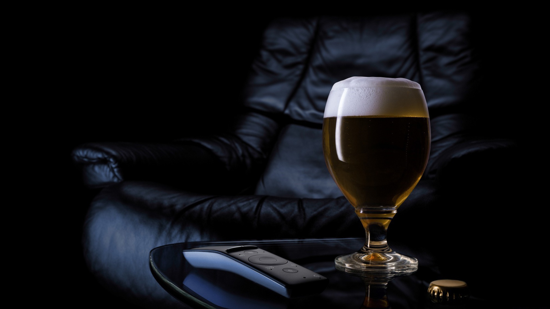 Бокал пива на фоне черного кожаного кресла