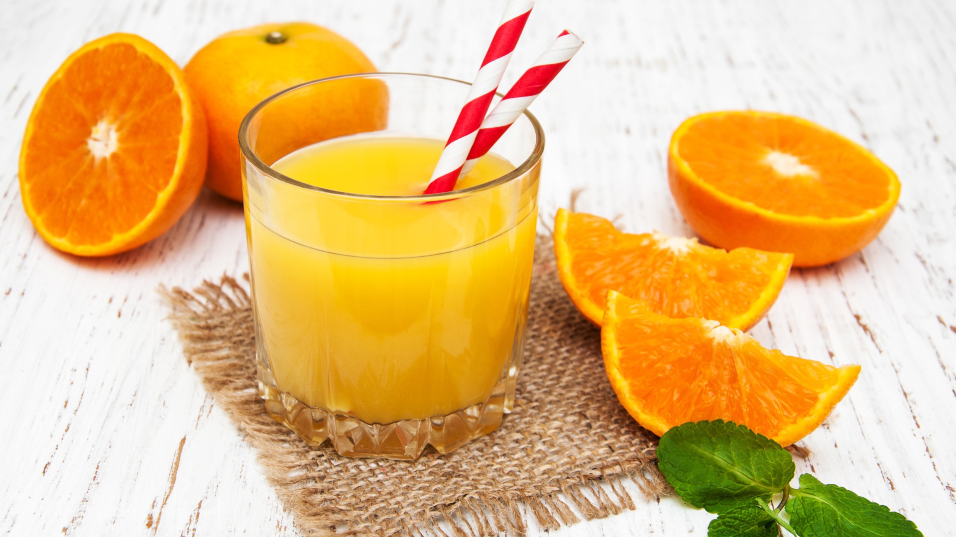 Стакан свежего сока на столе с апельсинами