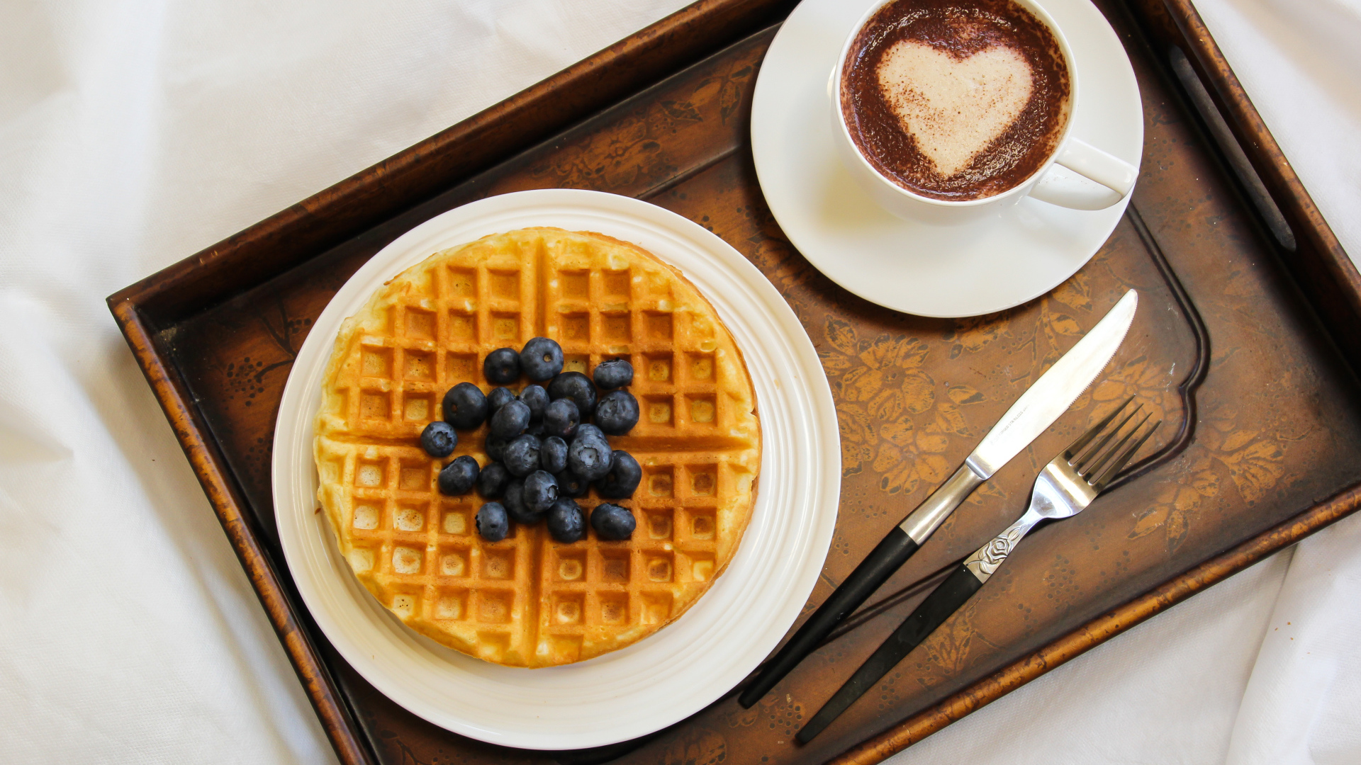 Капучино в чашке на подносе с вафлями и черникой 