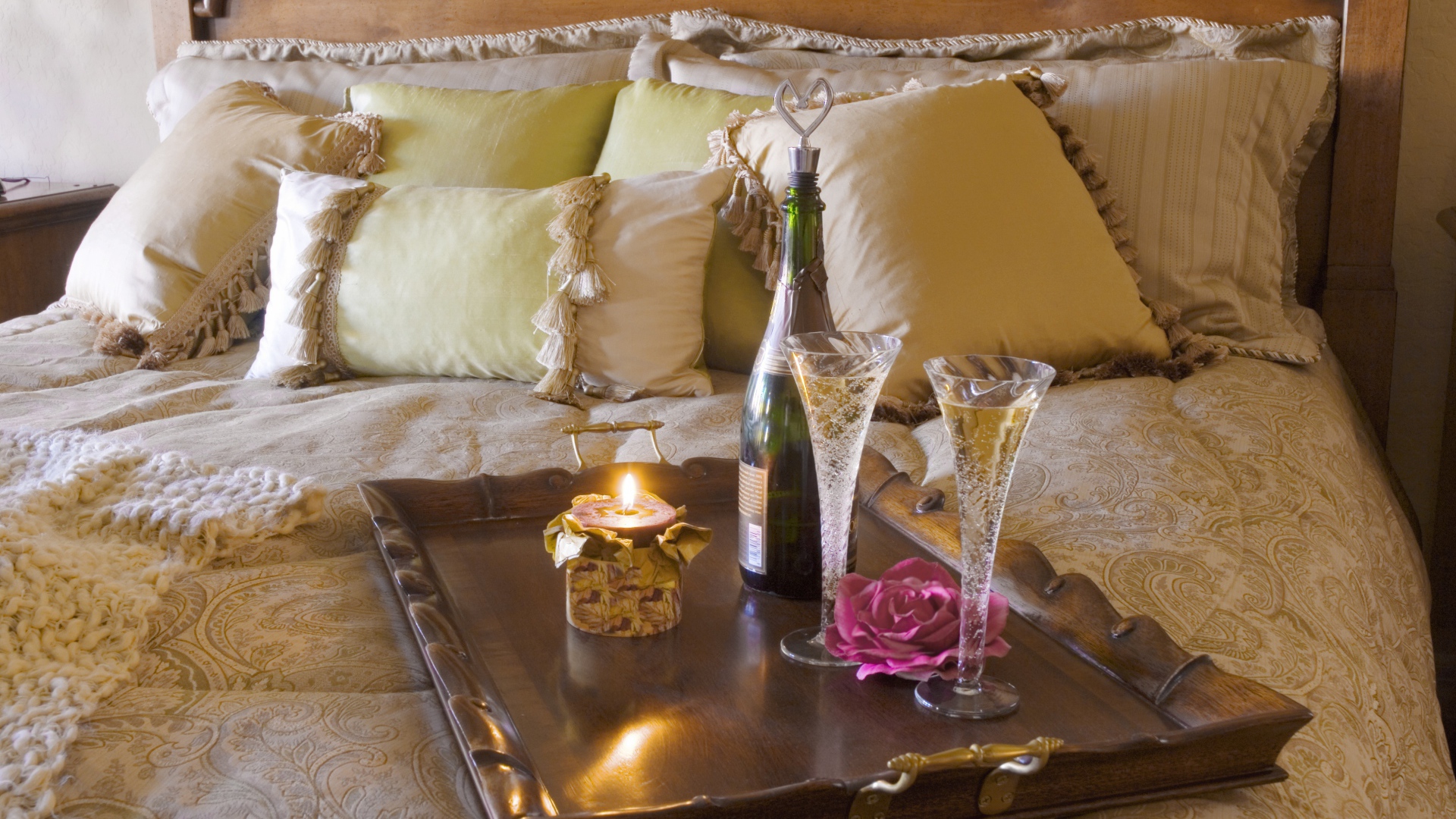 Шампанское с бокалами и свечой на кровати 