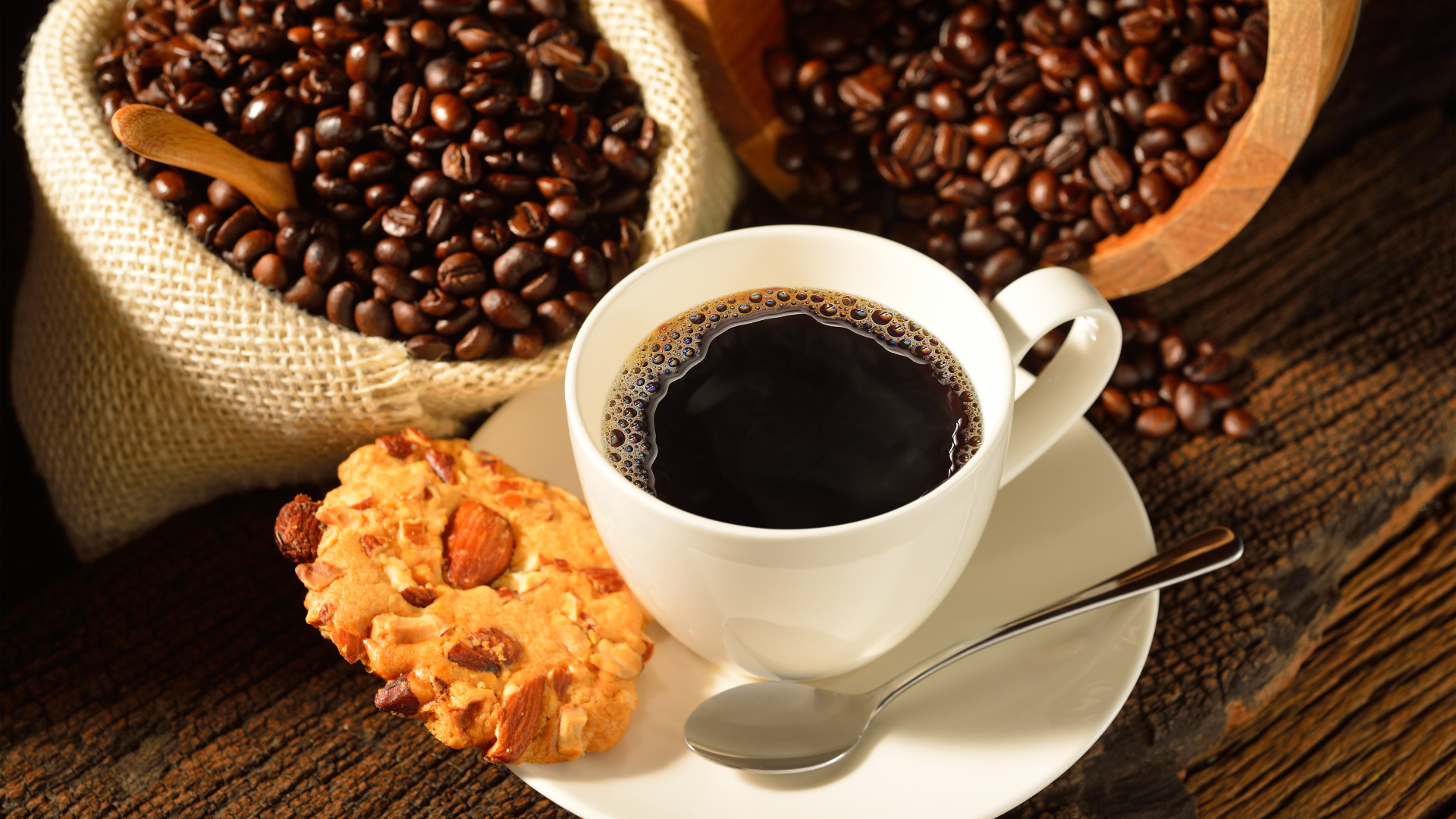 Кофейные зерна на столе с белой чашкой и печеньем