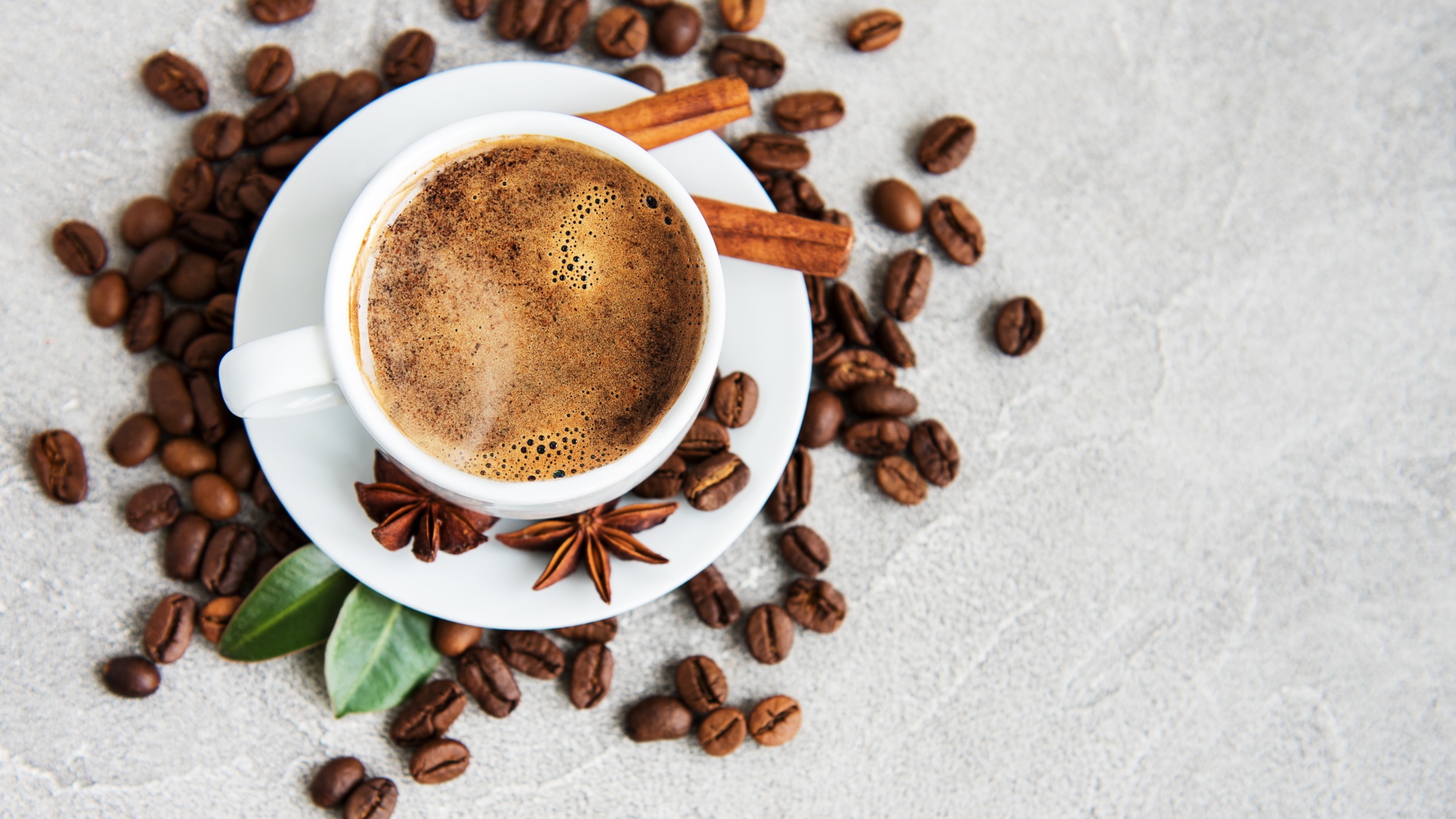 Чашка кофе с кофейными зернами на столе с корицей и бадьяном