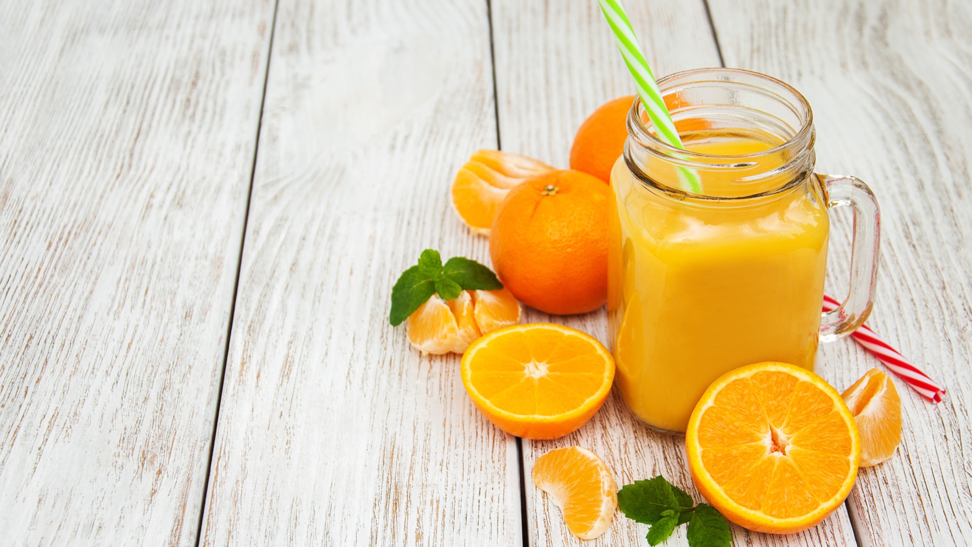 Свежий сок в стеклянной банке на столе с апельсинами