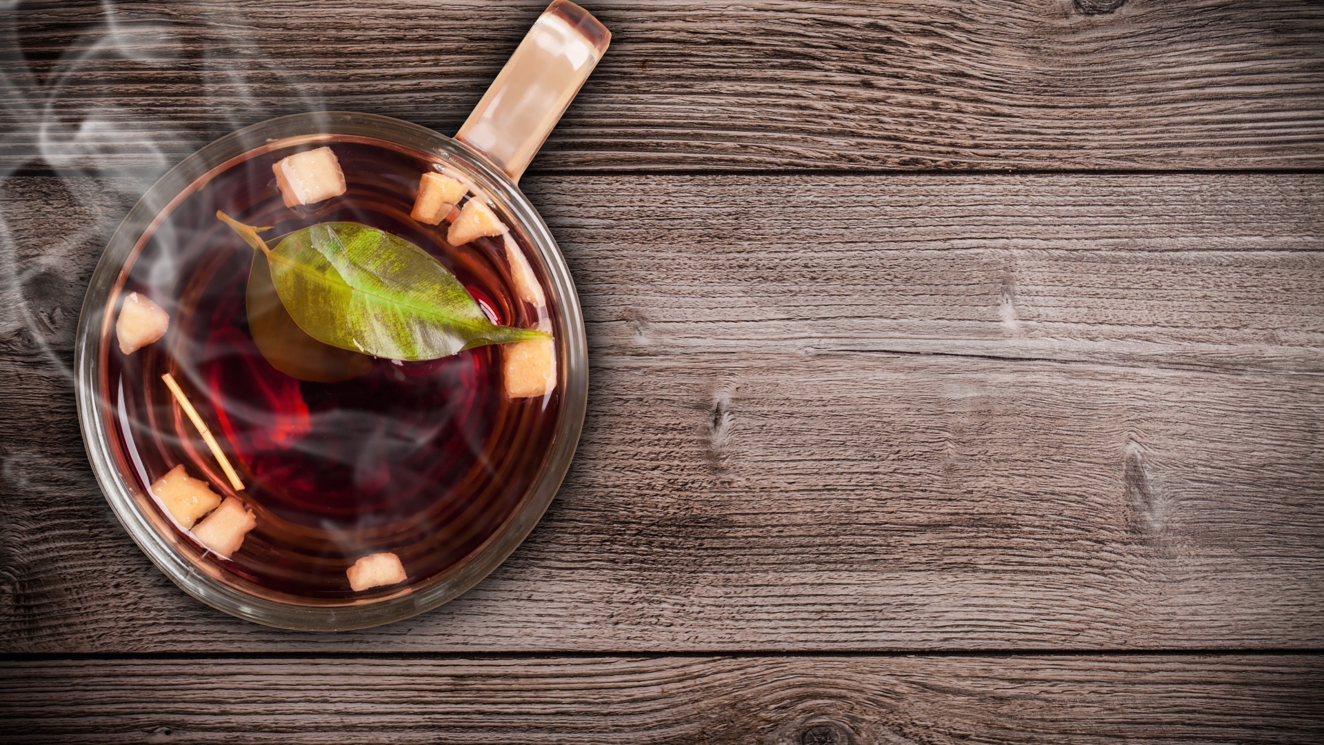 Стеклянная чашка горячего чая на деревянном столе