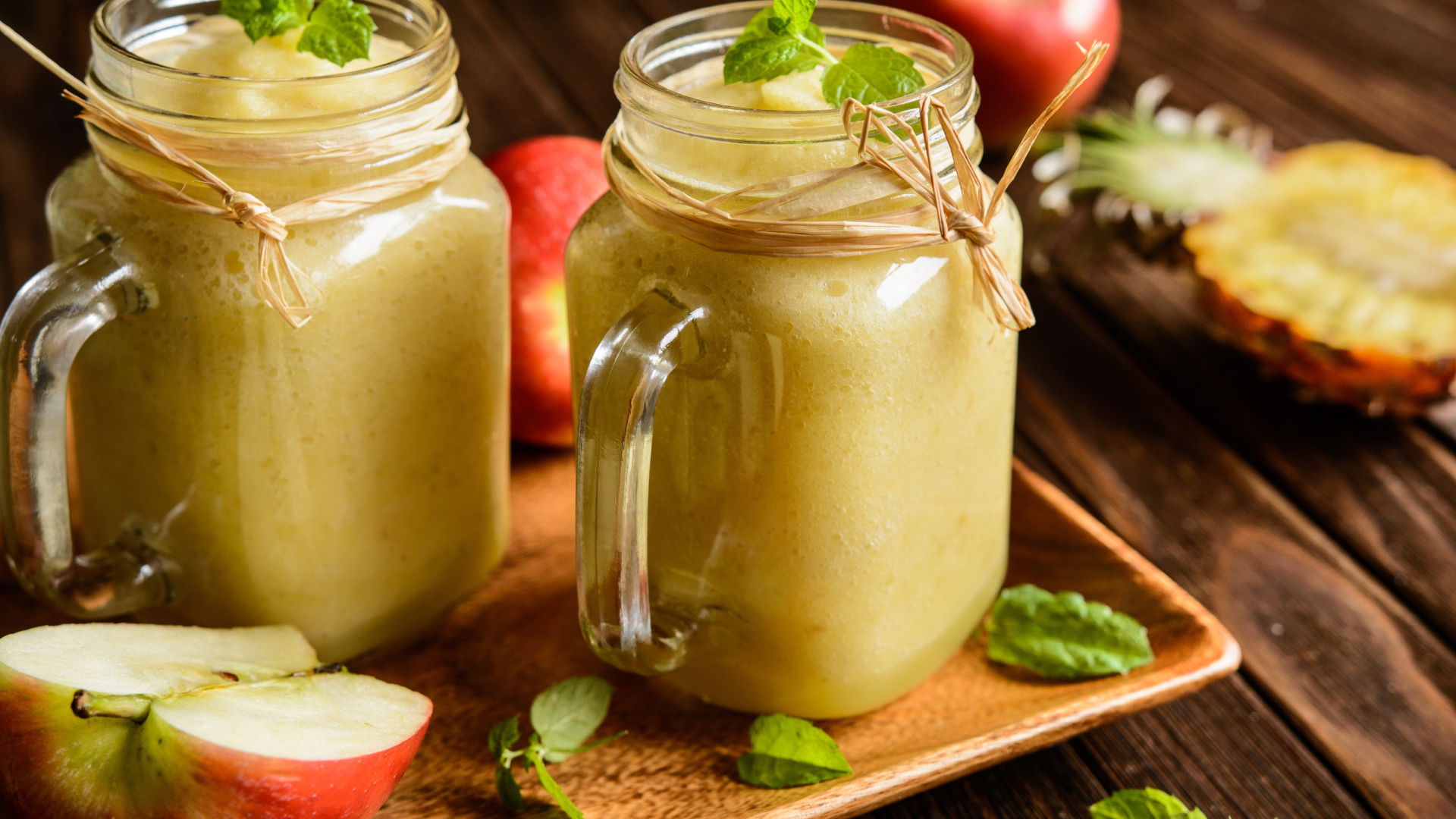 Смузи в стеклянных банках на столе с яблоками