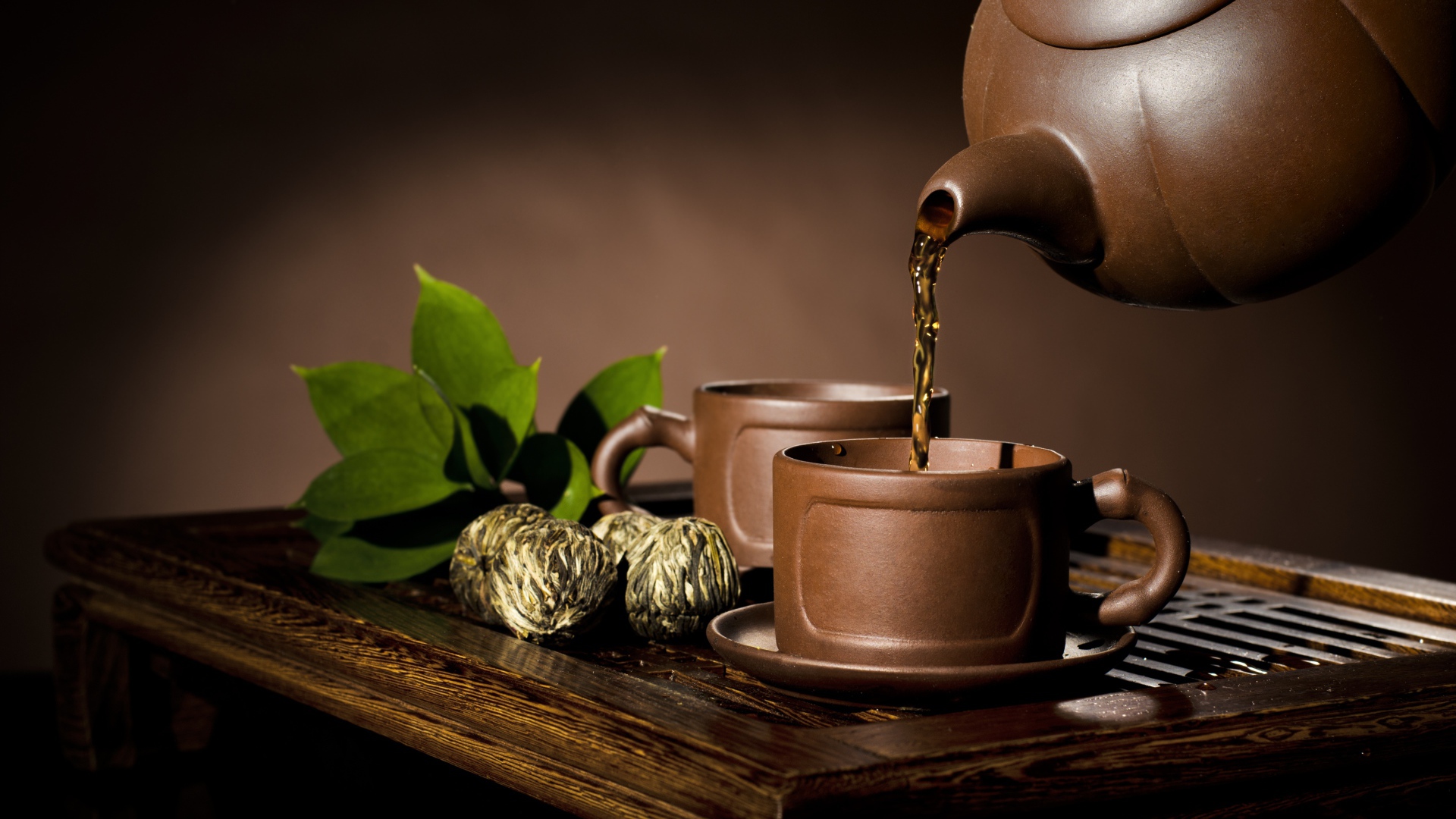 Чай наливают из чайника в коричневую чашку
