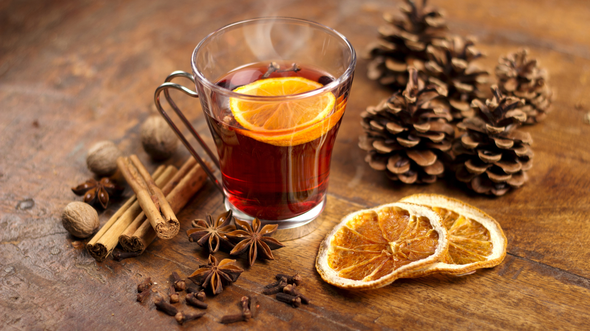 Чай с лимоном в чашке на столе с корицей, бадьяном и шишками