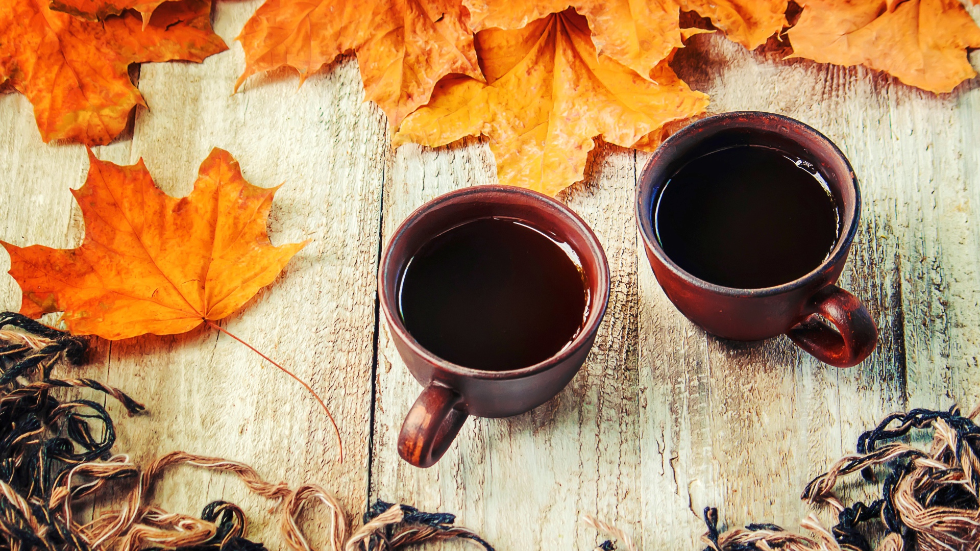 Две чашки горячего кофе на столе с сухими листьями