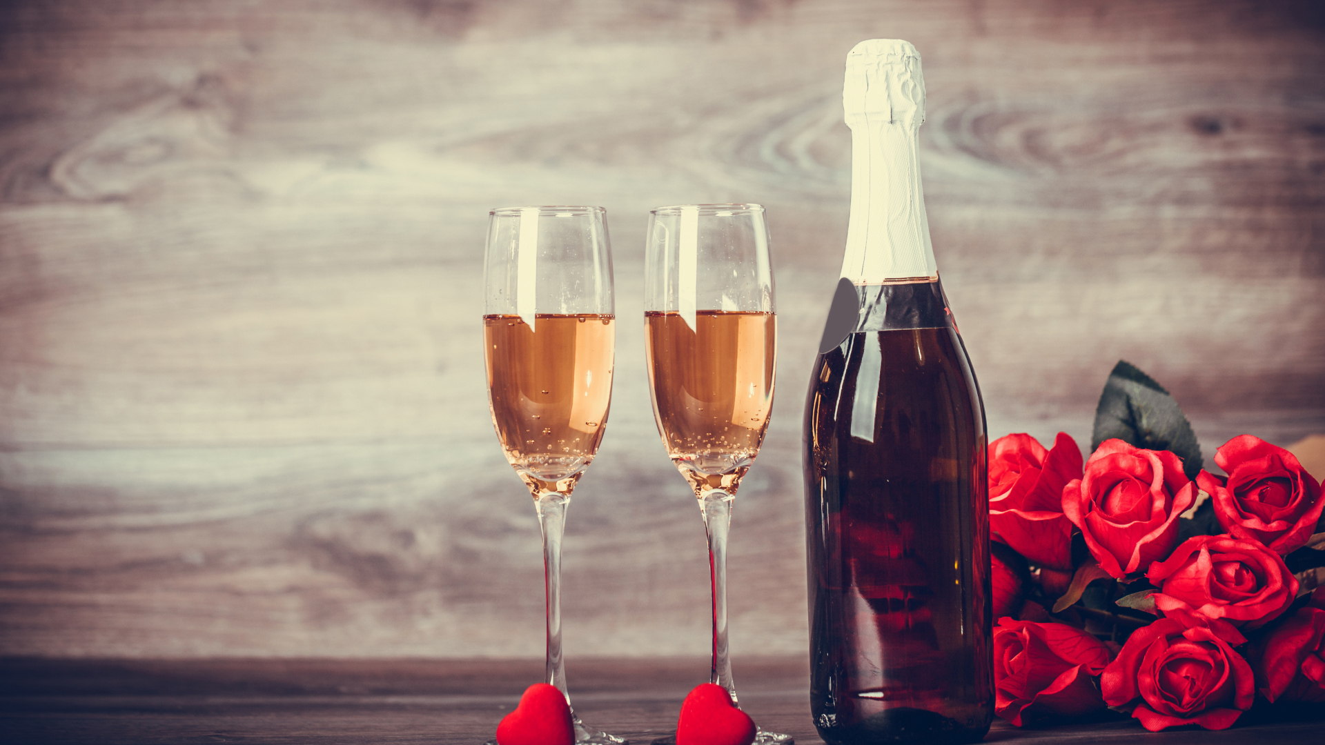 Два бокала и бутылка шампанского на столе с букетом роз