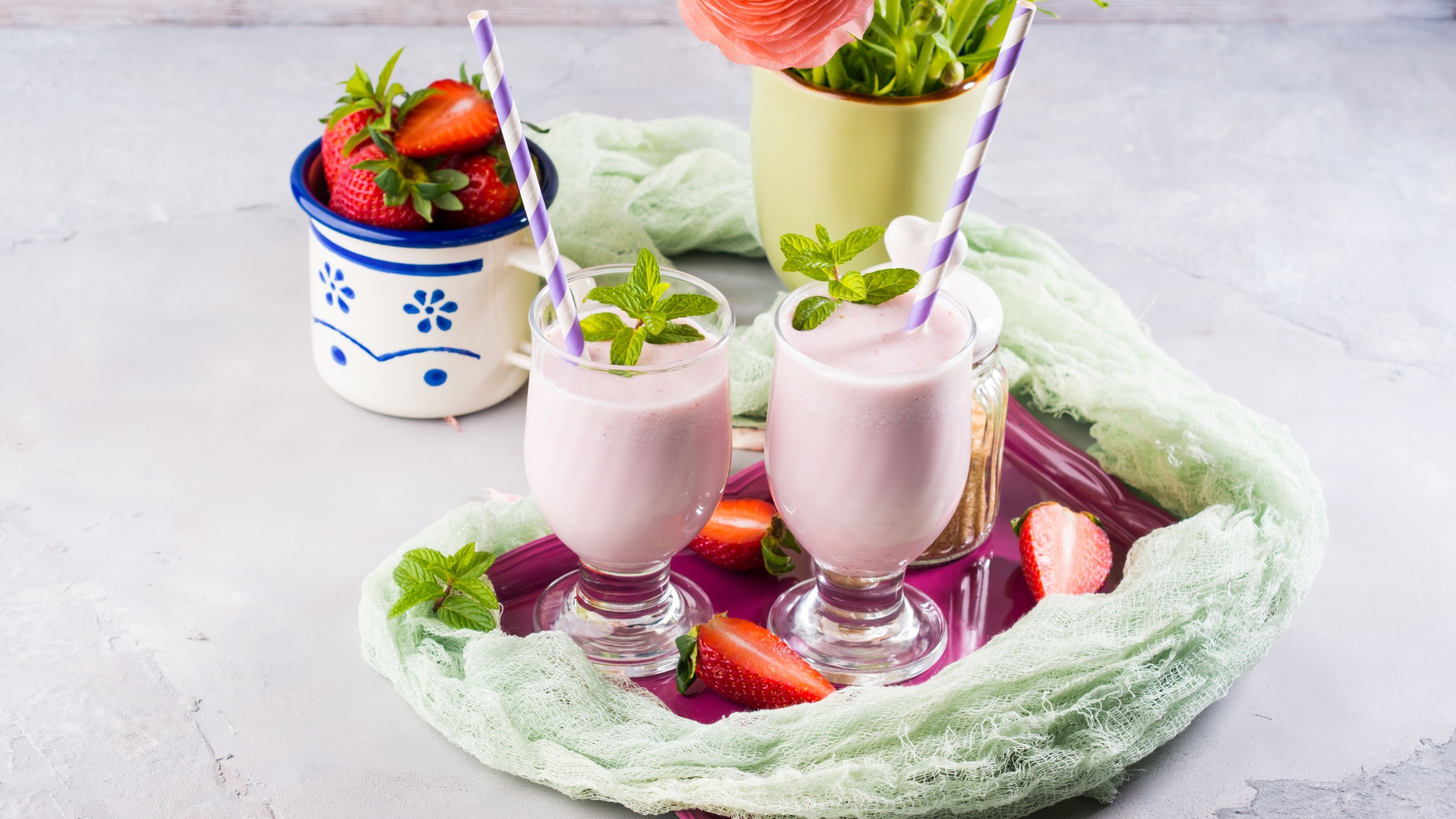 Два стакана с коктейлем на столе с букетом и клубникой