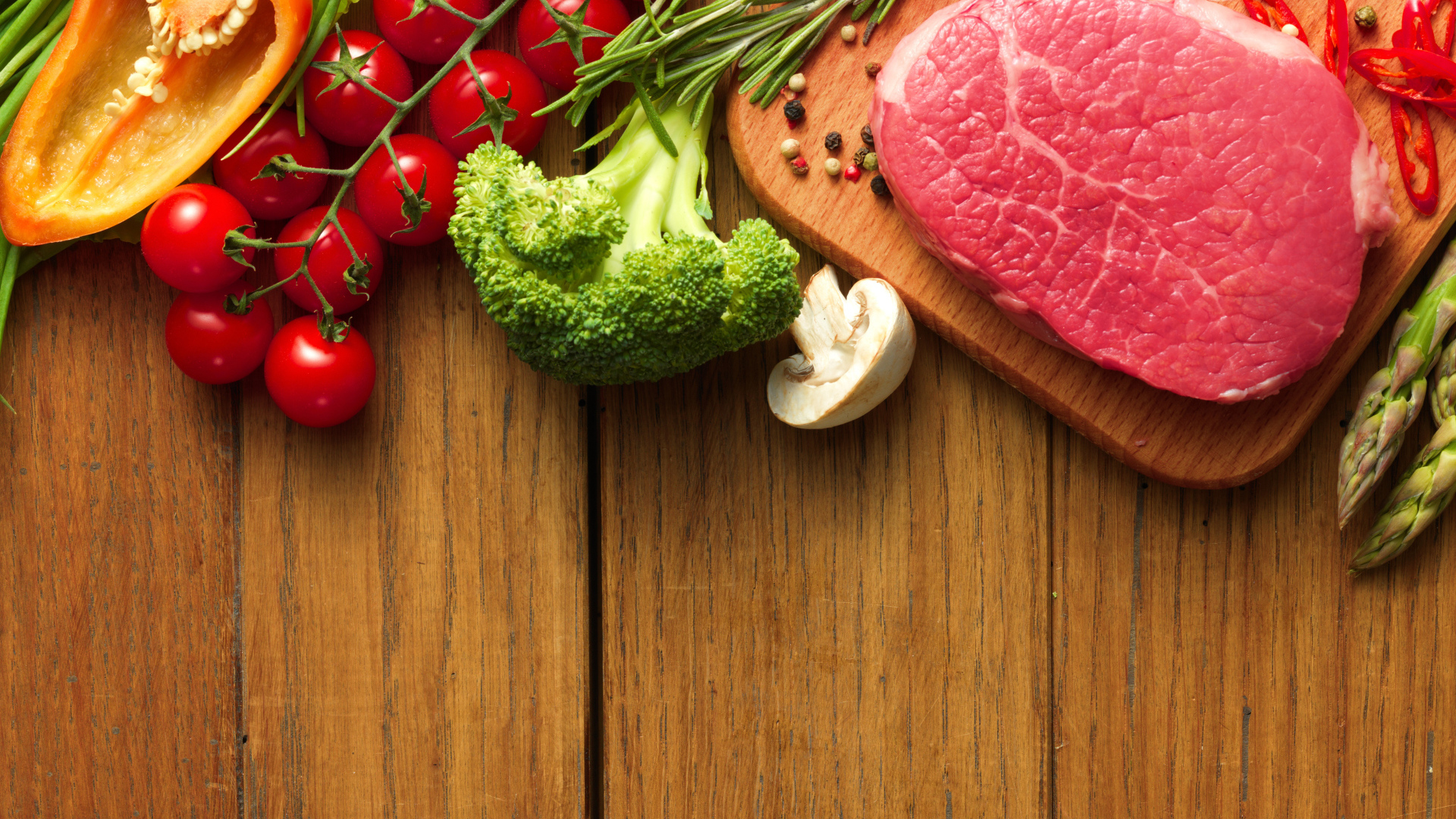 Кусок свежего мяса на столе с овощами и зеленью 